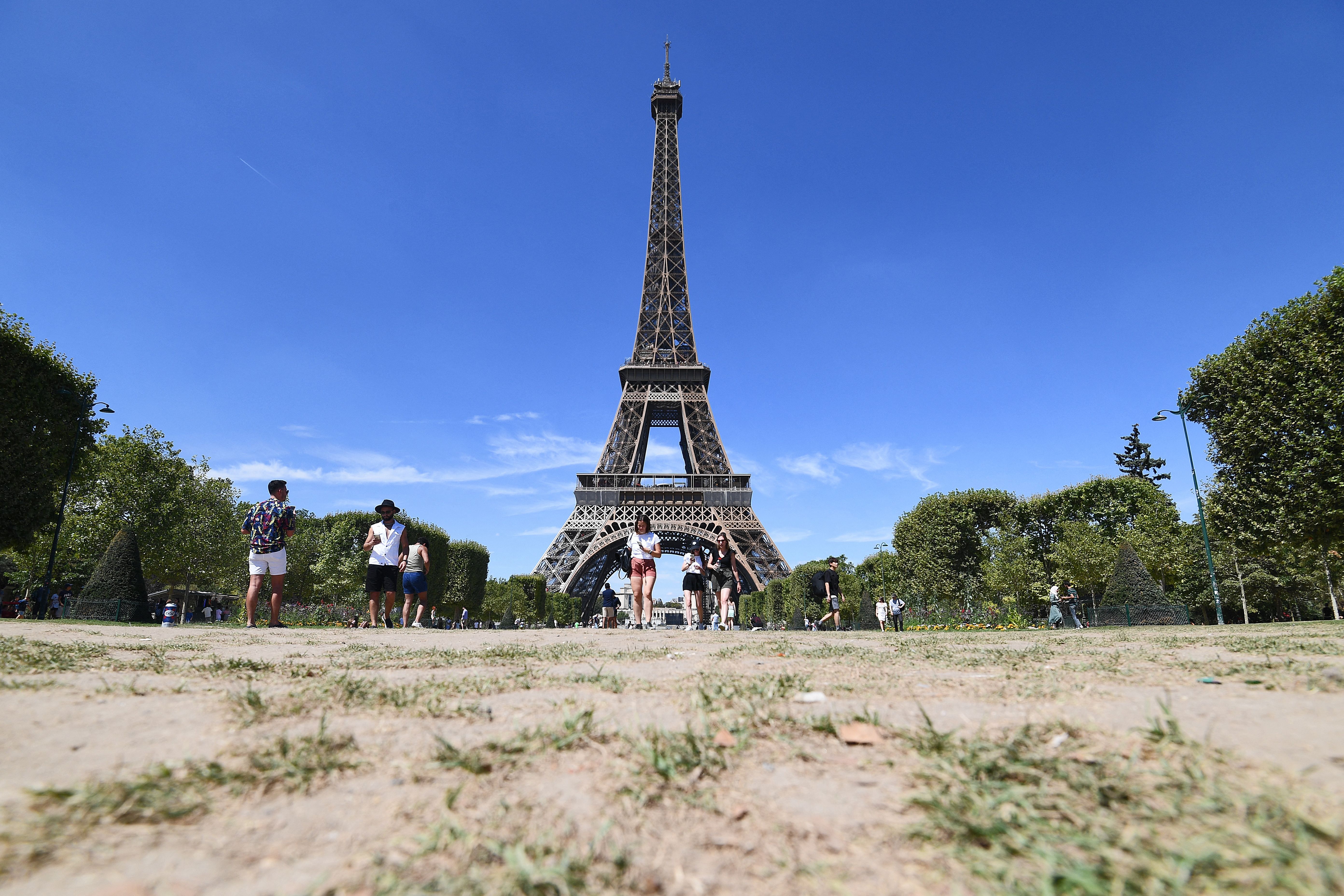 People walk on the parched Champ de Mars in front of the Eiffel Tower in Paris on August 3, after France recorded its driest July ever. 