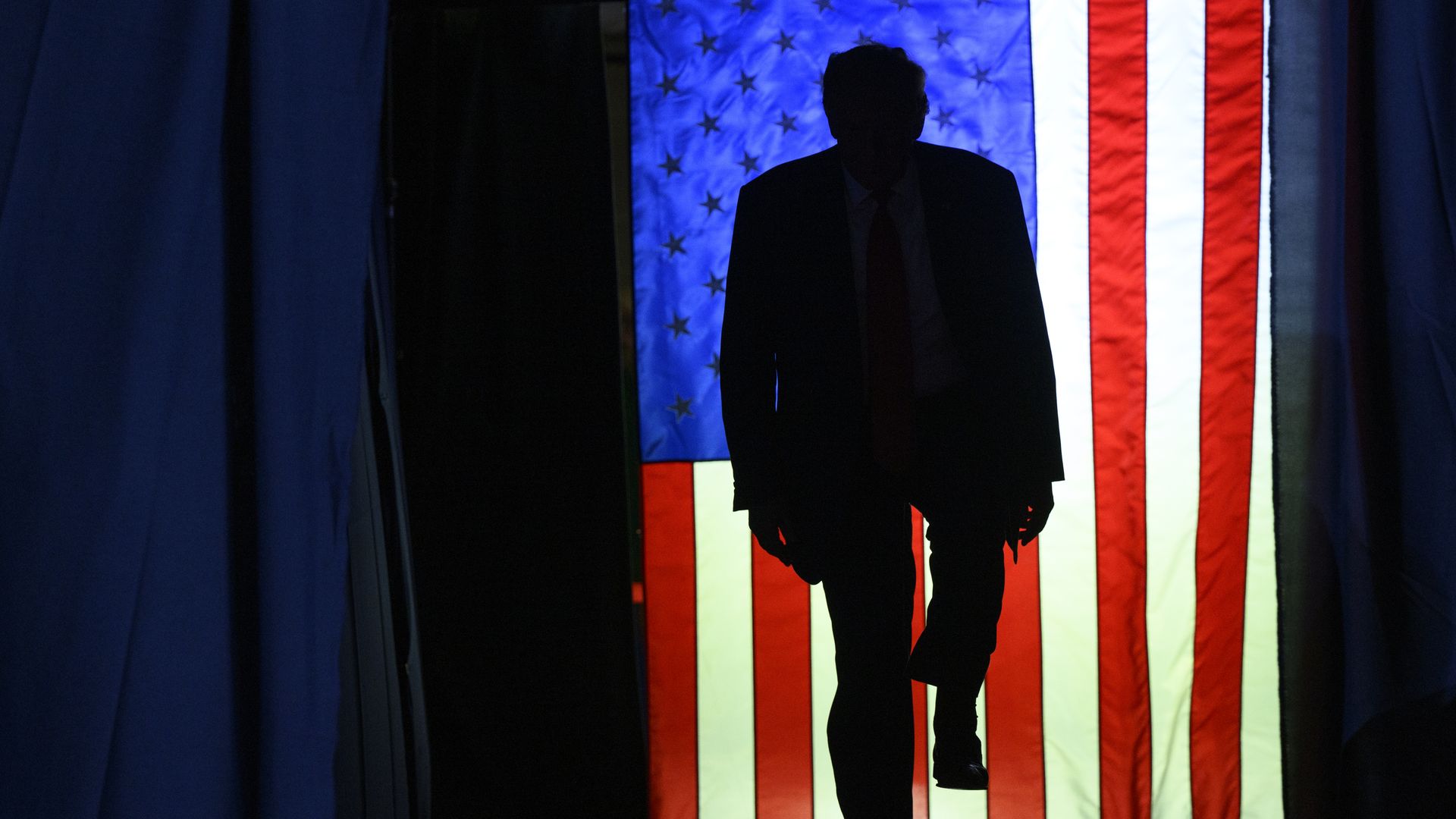 A silhouette of former President Trump in front of an American flag.