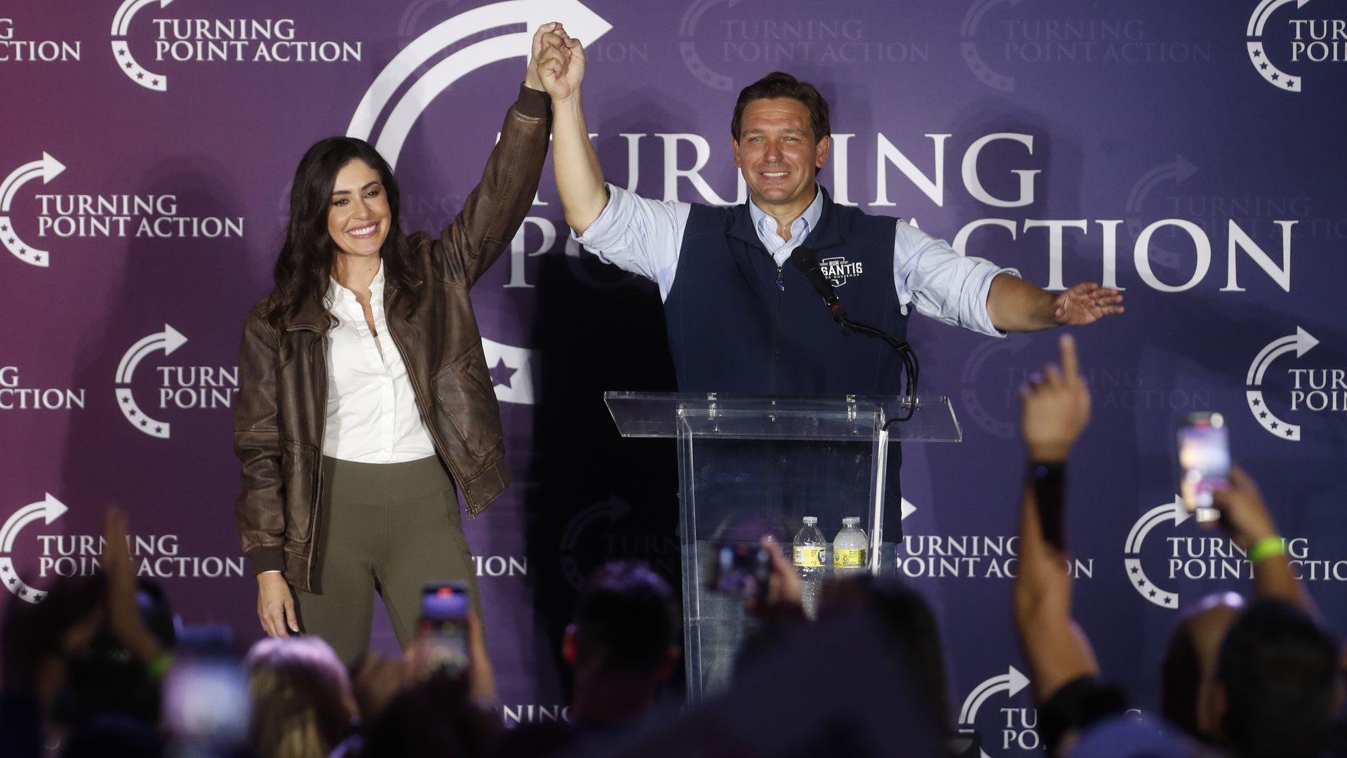 Ron DeSantis holds up Anna Paulina Luna's arm as a crowd cheers at a rally