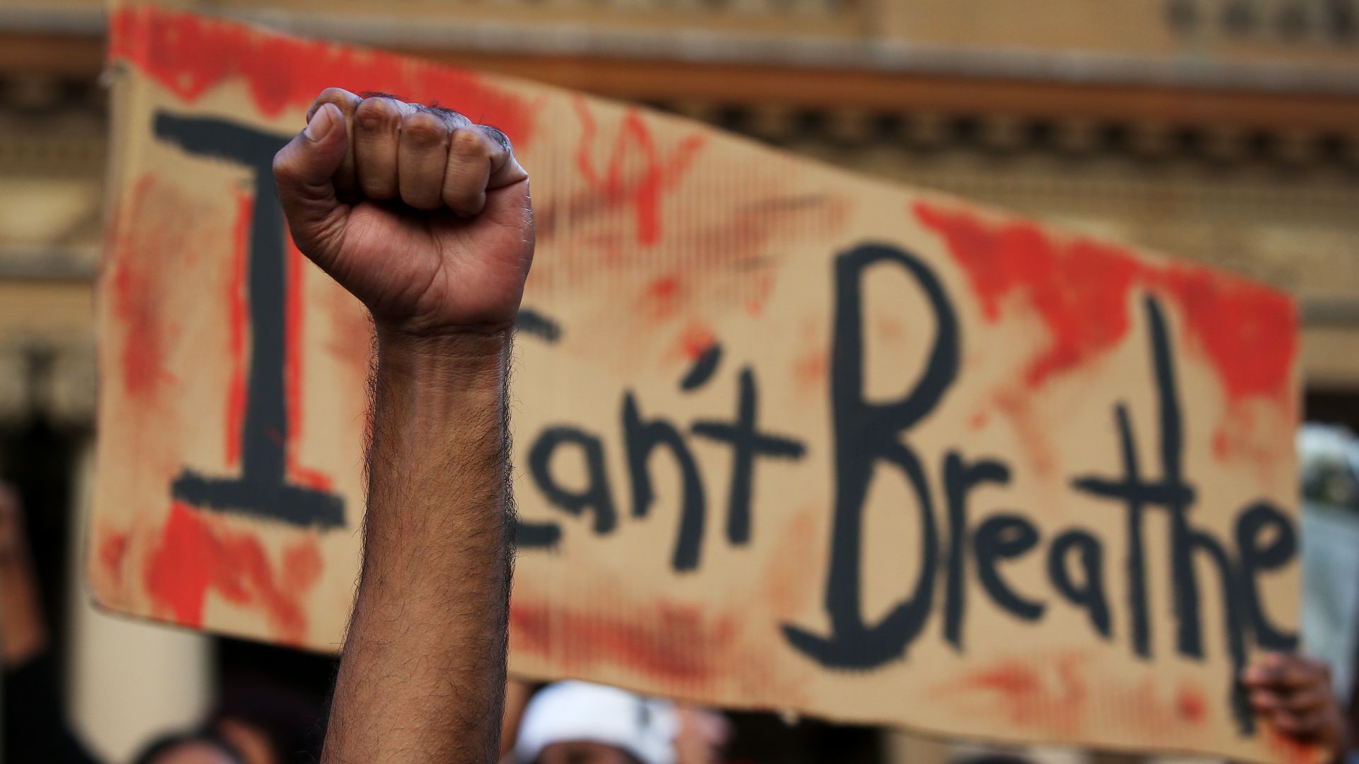 A man holds his fist in the air in front of a placard that reads 'I can't breathe' at Town Hall in solidarity with protests in the United States on June 06, 2020 in Sydney, Australia. 