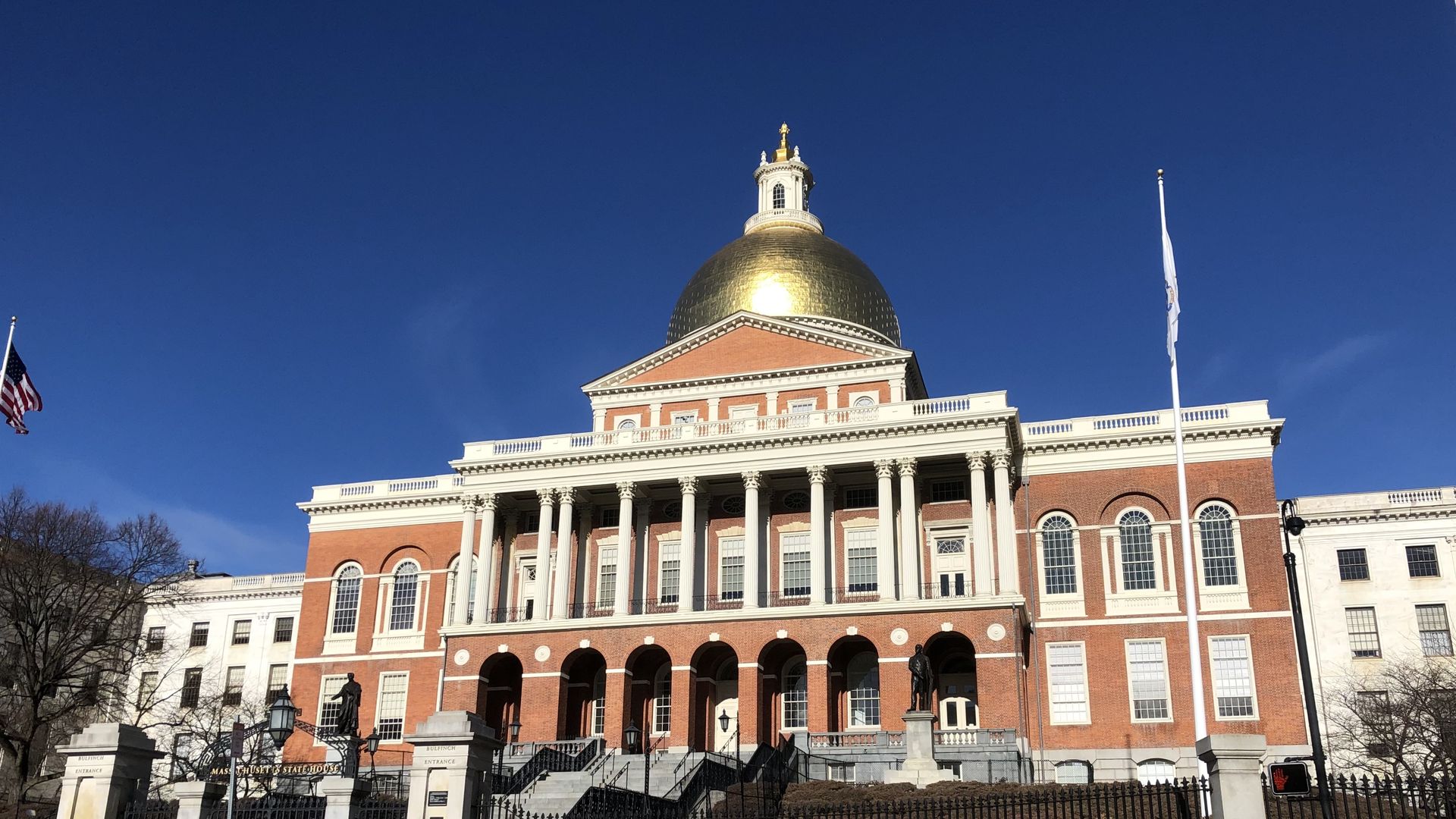 People walk in front of the Massachusetts State House on Beacon Street.