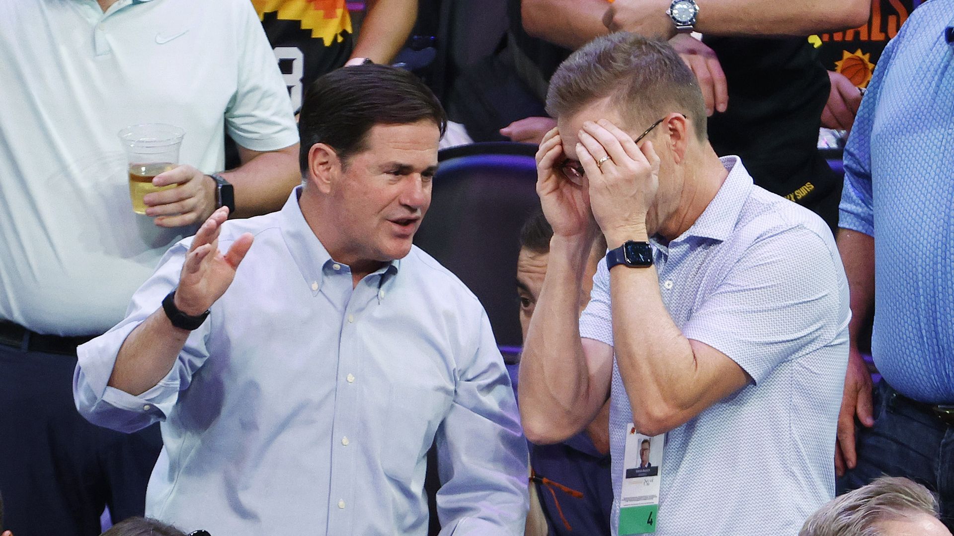 Doug Ducey talking to a male at a basketball game