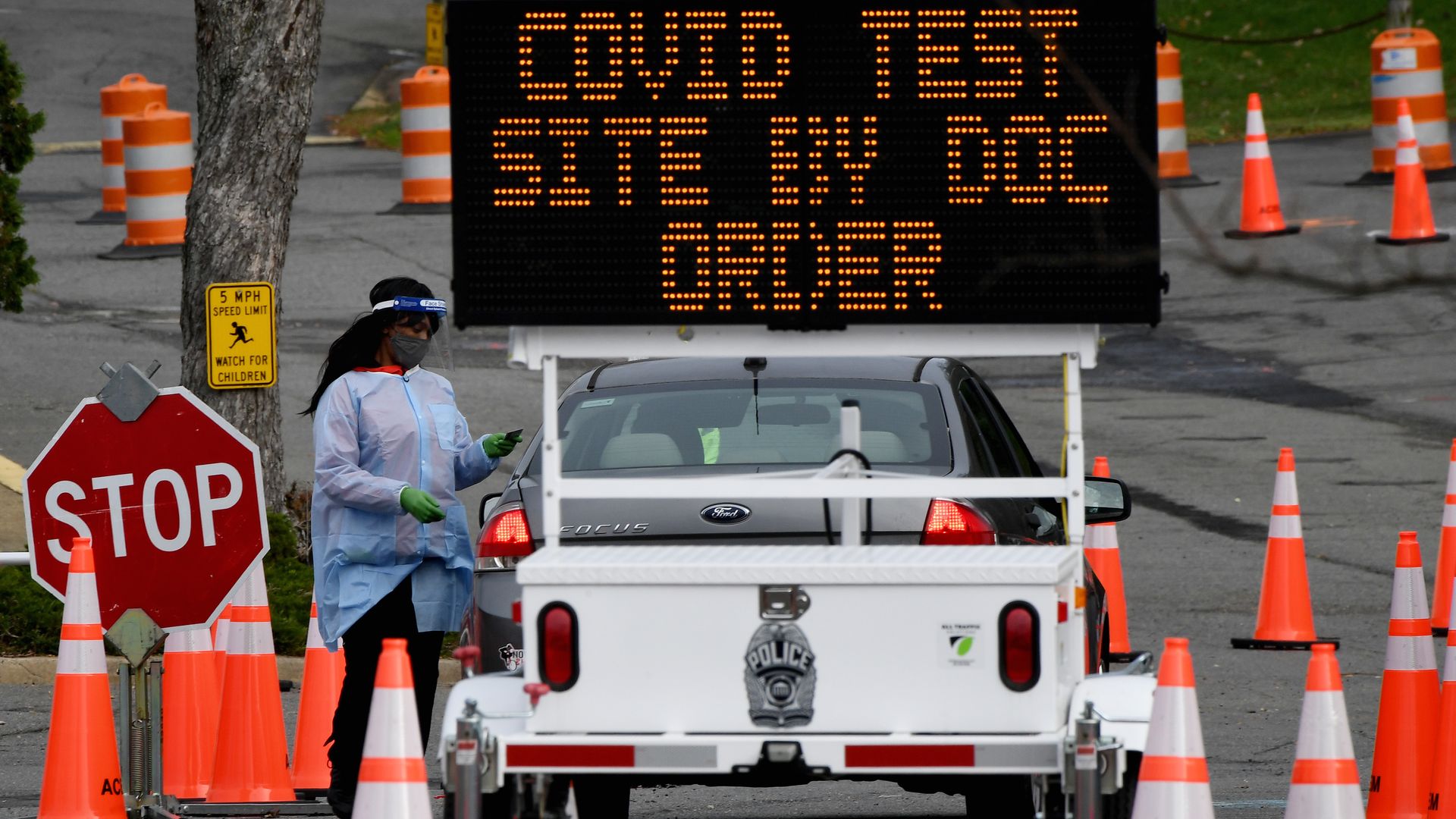 A healthcare worker oversees cars as people arrive to get tested for coronavirus at a testing site in Arlington, Virginia, on December 1