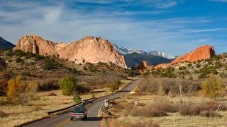 A pickup truck drives on a road near The Garden of the Gods in Colorado Springs, Colorado. 