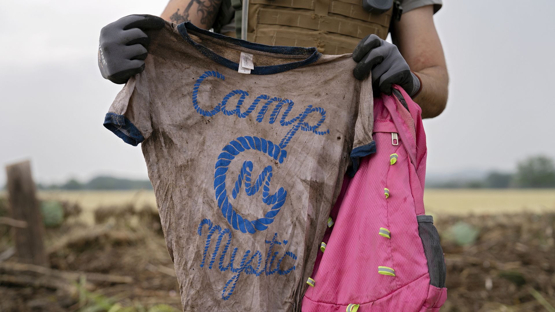 A search and rescue volunteer holds a T-shirt and backpack with the words "Camp Mystic" on them in Comfort, Texas on July 6 following deadly flooding in the area.