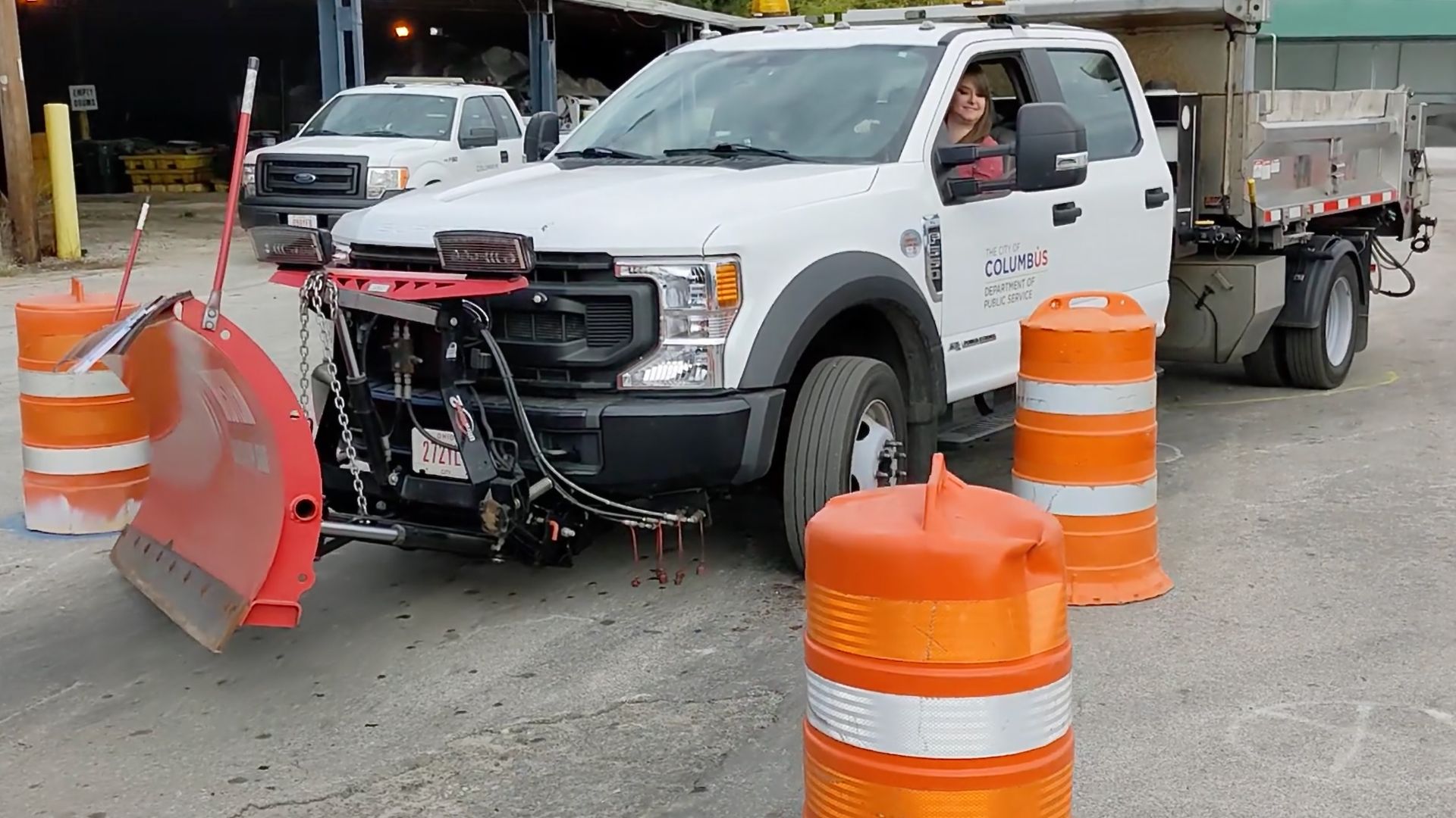 Alissa maneuvers a snowplow through orange construction barrels