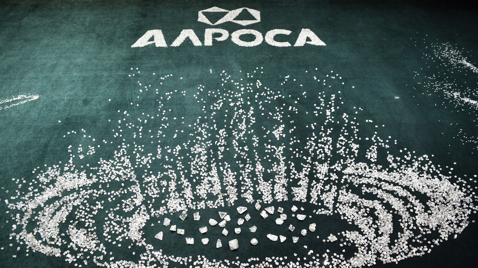 Diamonds scattered on a table under the Alrosa logo