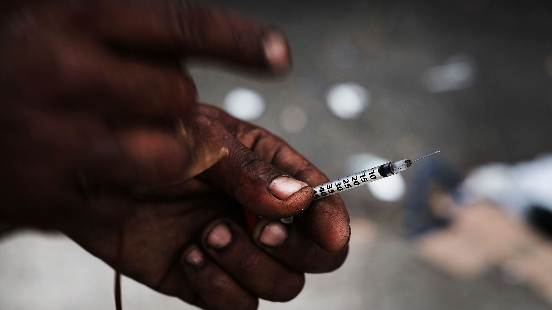 Photo of a heroin user's hand, holding a needle
