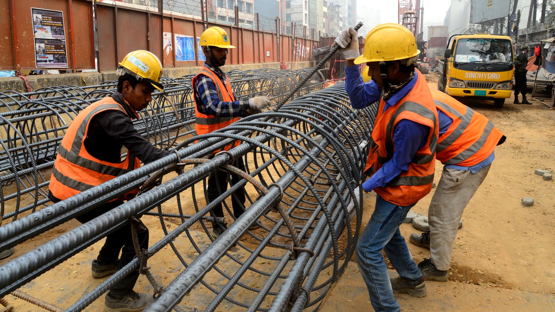 Bangladeshi workers preparing reinforcing steel at a construction site in Dhaka