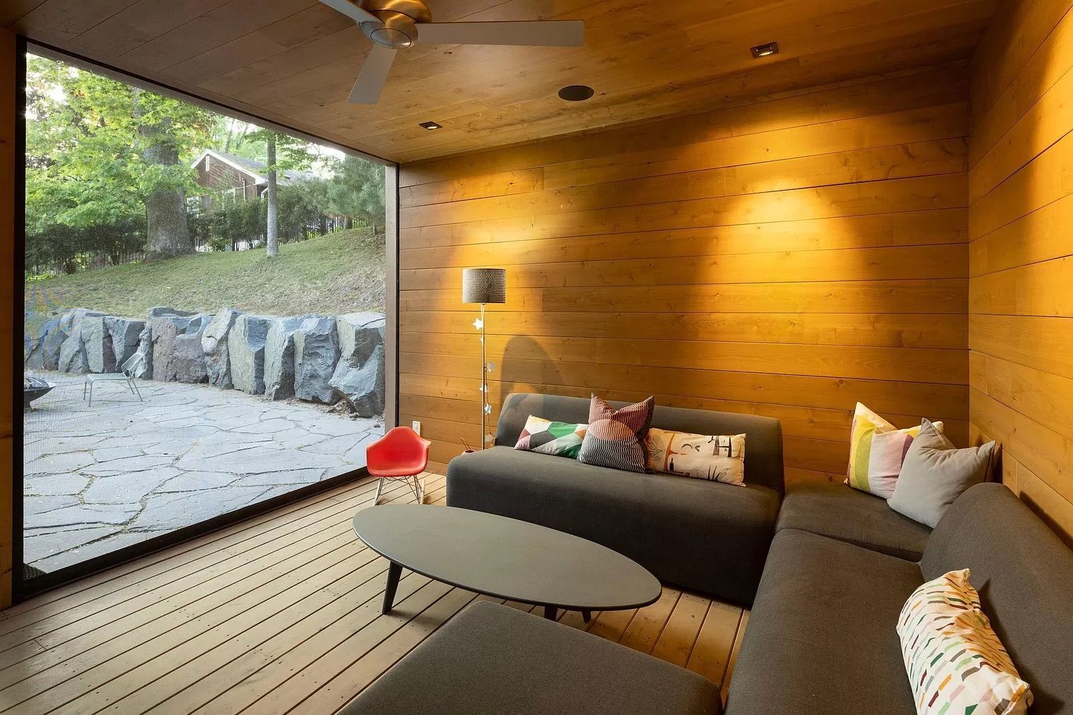 A living room with gray couches and wood walls.
