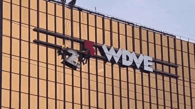 The number 2 being removed from the 102.5 WDVE sign off of a gold-glass building outside of Pittsburgh, PA