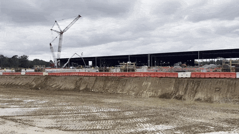 A pan across a large, steel-frame building under construction.