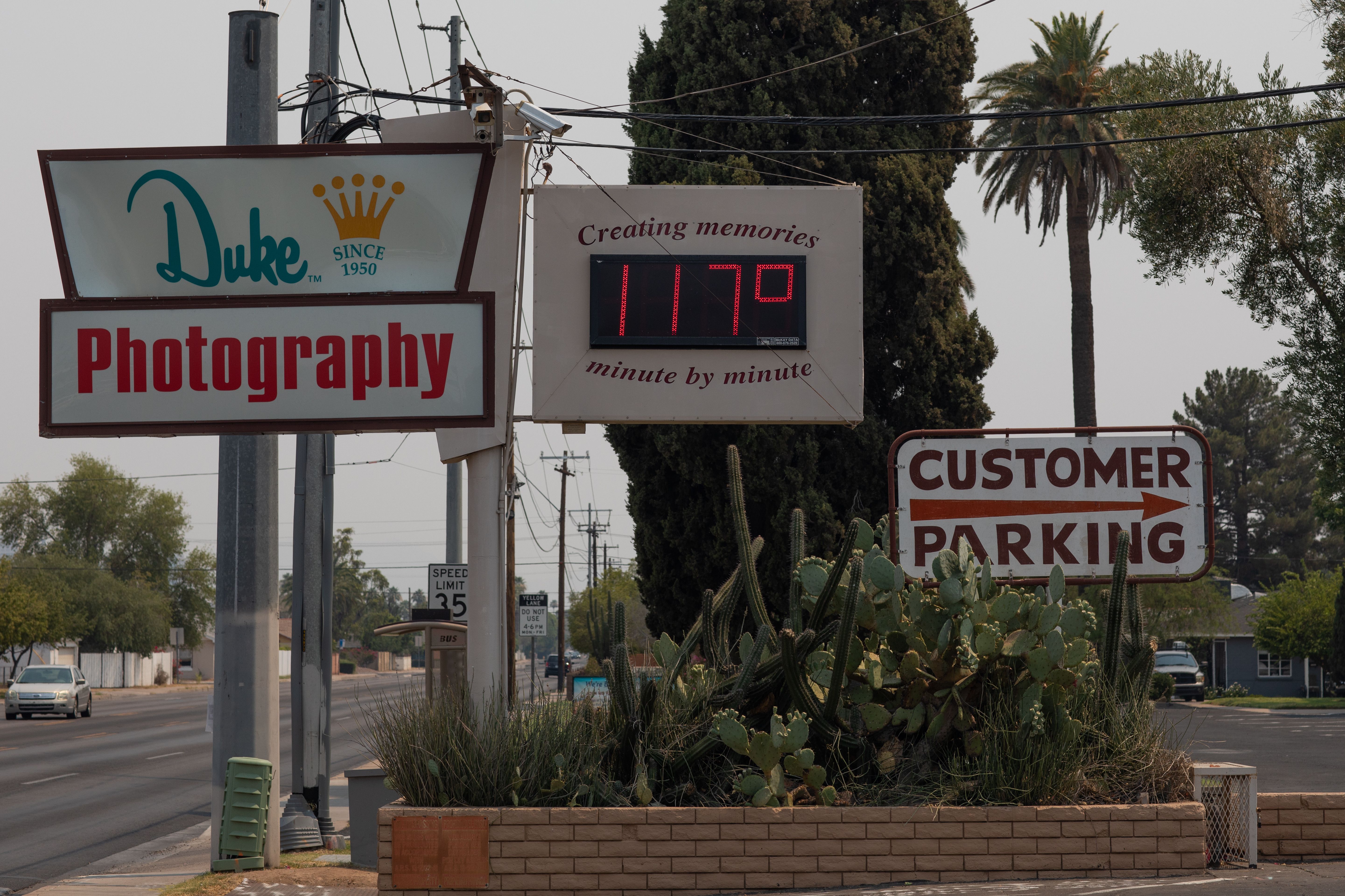A thermometer sign displays a temperature of 117 degrees Fahrenheit 