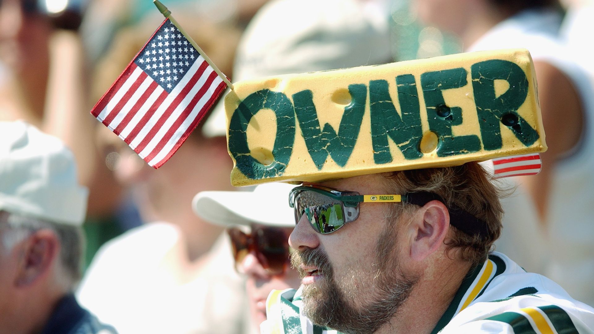 A fan of the Green Bay Packers wears a cheese head with the word owner during the game against the Atlanta Falcons at Lambeau Field.