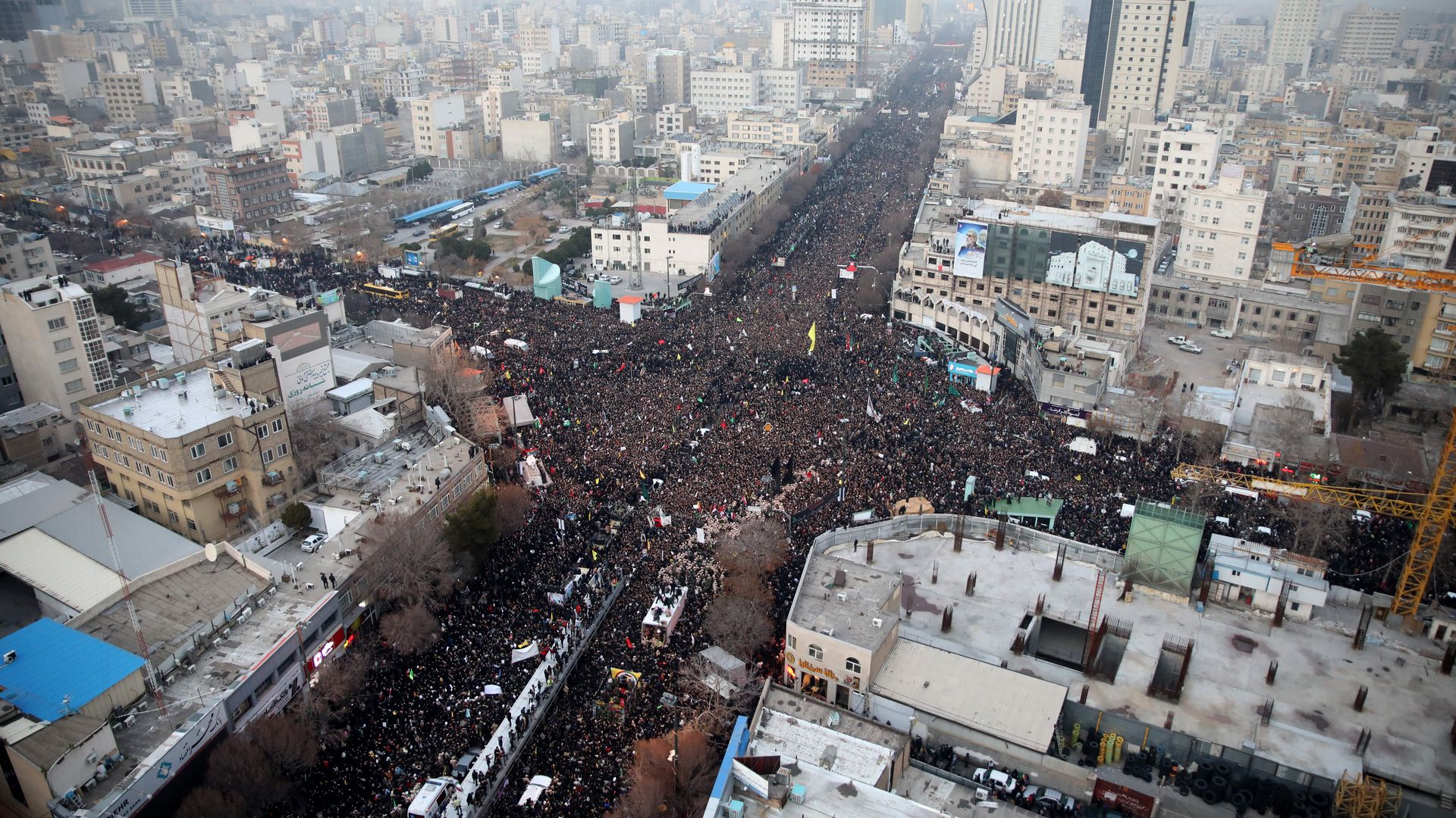 Iranians march behind a vehicle carrying the coffins of slain major