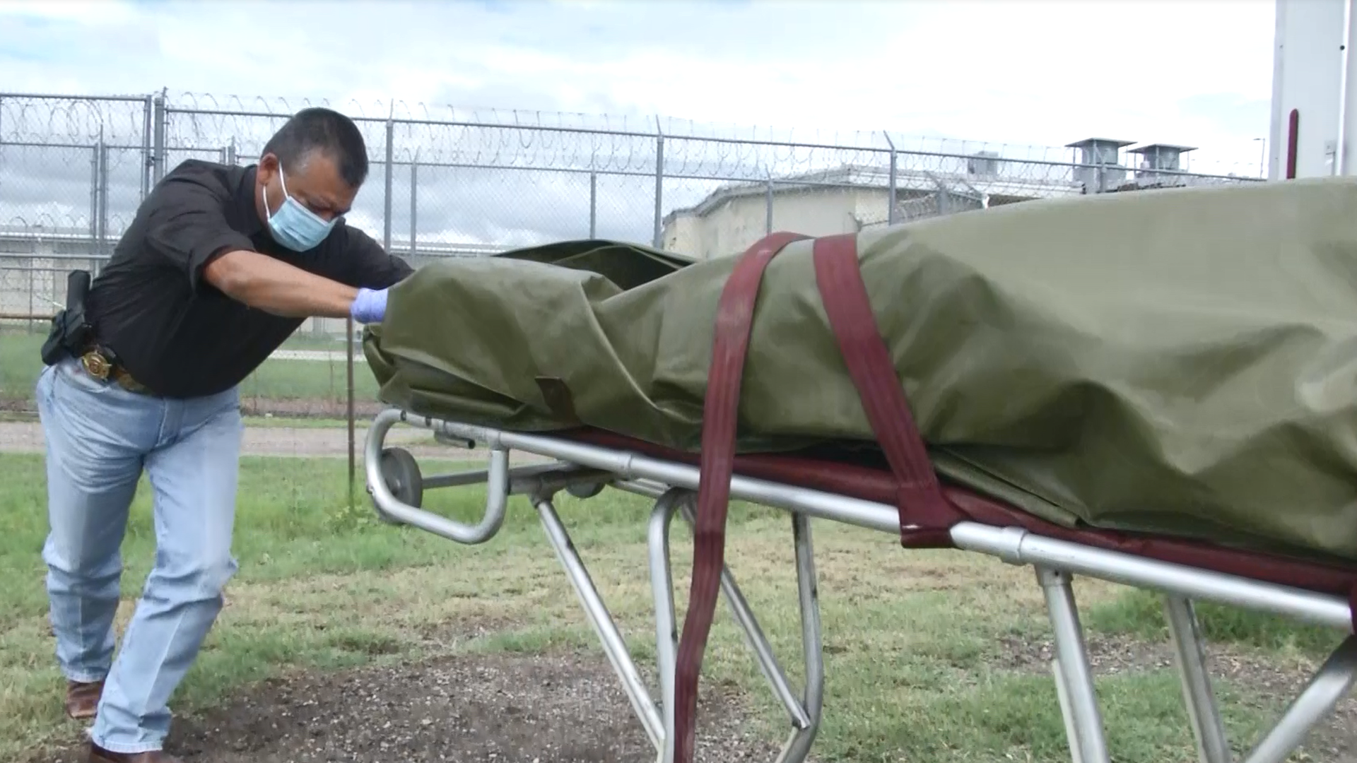 Picture of a man pushing a cart with a filled body bag