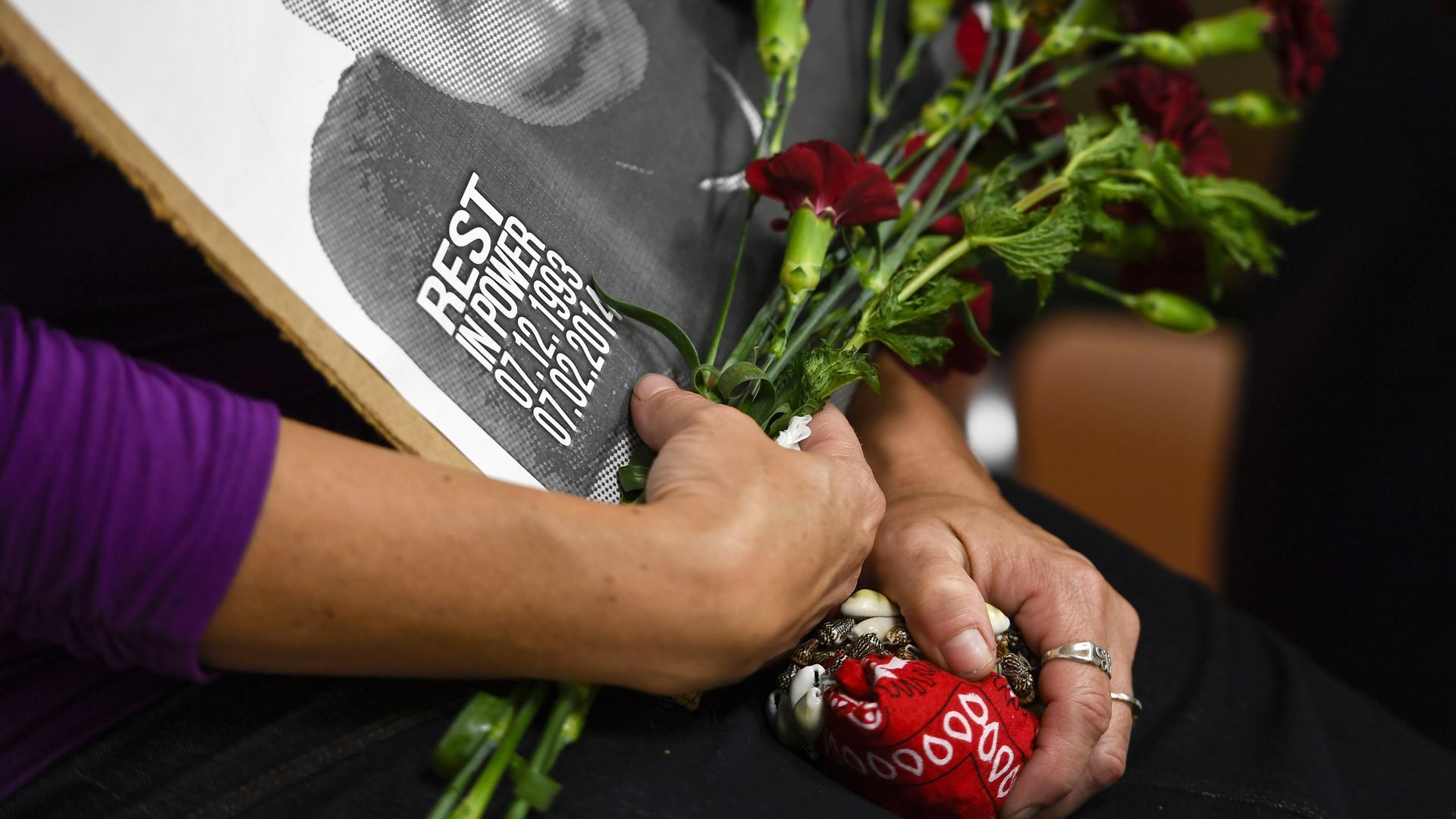 A picture of arms holding flowers and a picture of a young man killed by police