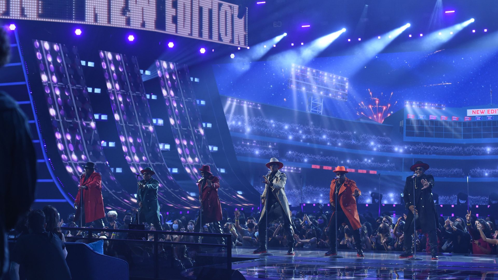 All six members of New Edition perform at the 2021 American Music Awards, singing on stage with a huge electronic screen that read "New Edition" displayed on top. 