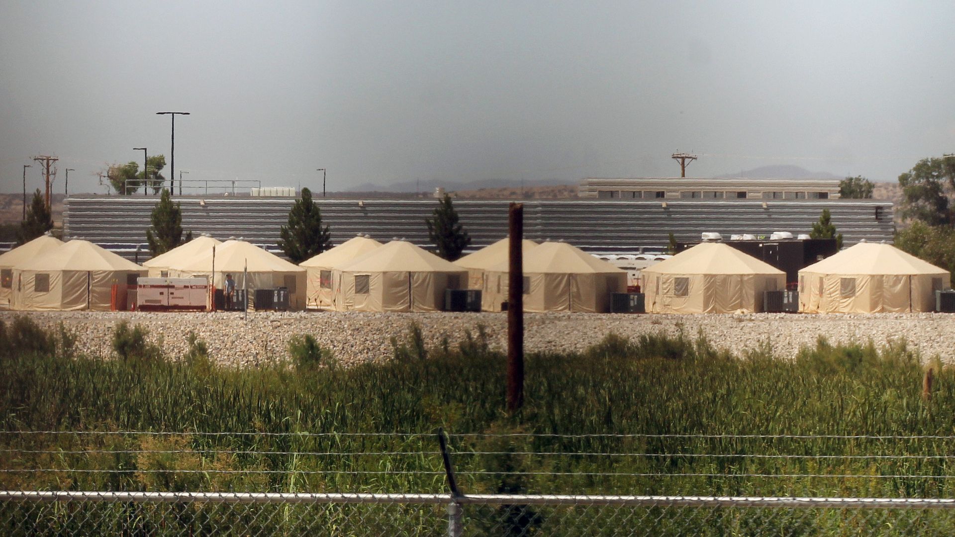 Tents set up behind a barbed wire fence that are used for detaining immigrants. 