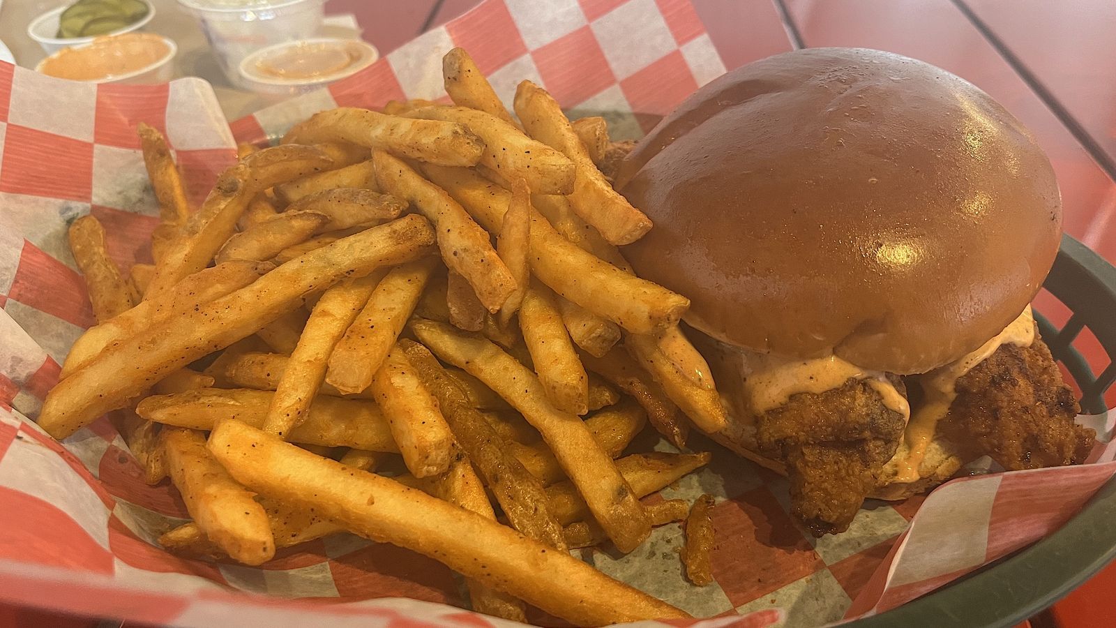 A chicken sandwich next to a bed of fries 