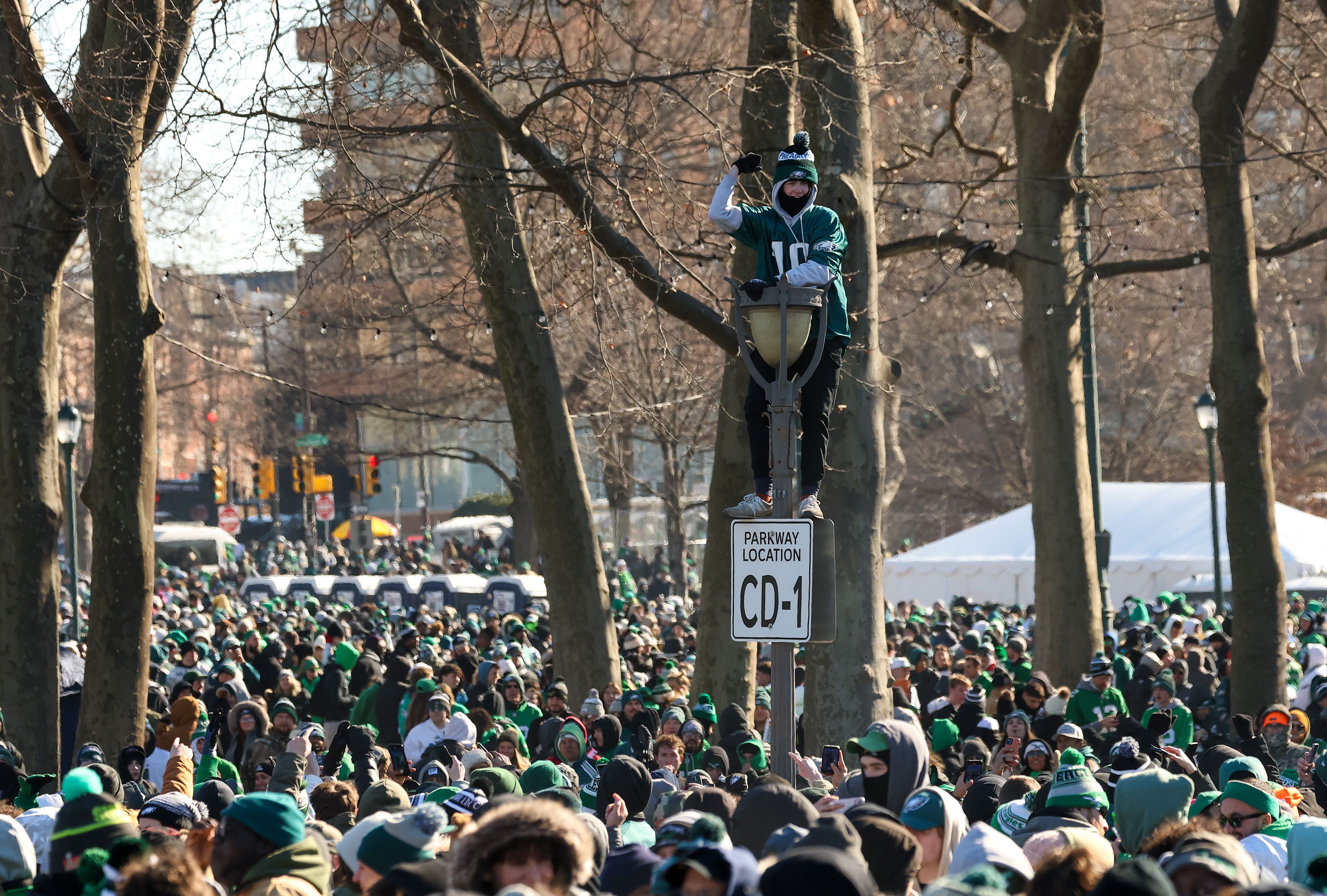 A fan climbs a lamppost before the parade.