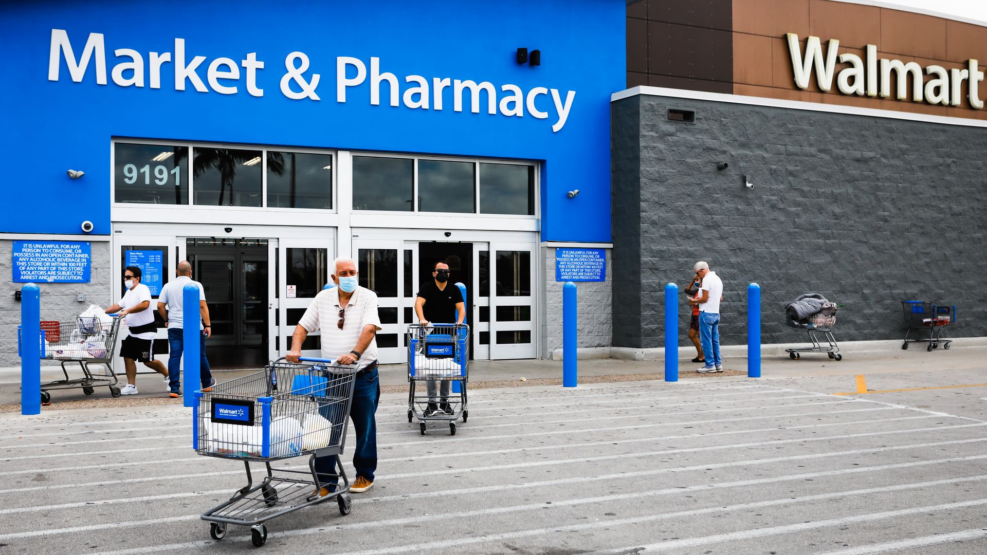 man pushing a shopping cart out of a Walmart store