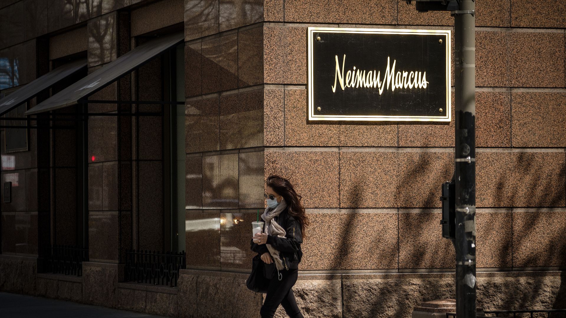 A pedestrian walks by a Neiman Marcus sign.