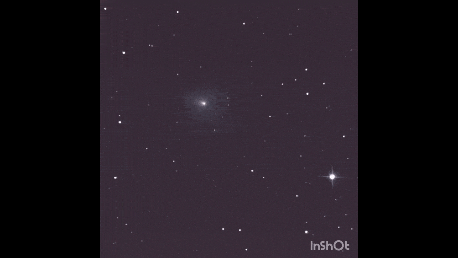 A comet streaking past stars in black and white