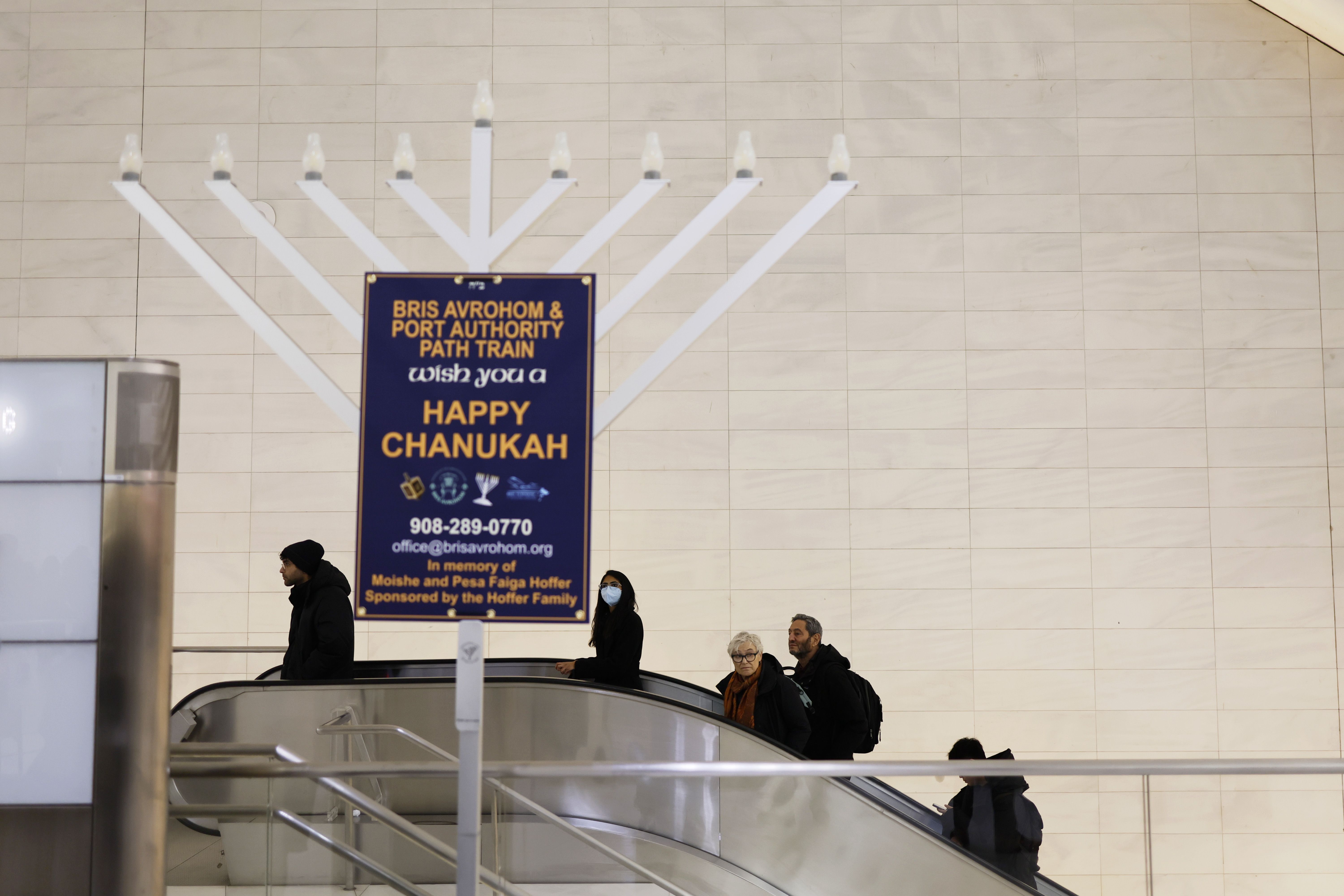 People ride an escalator past a Menorah lighting at the World Trade Center Oculus in New York City.