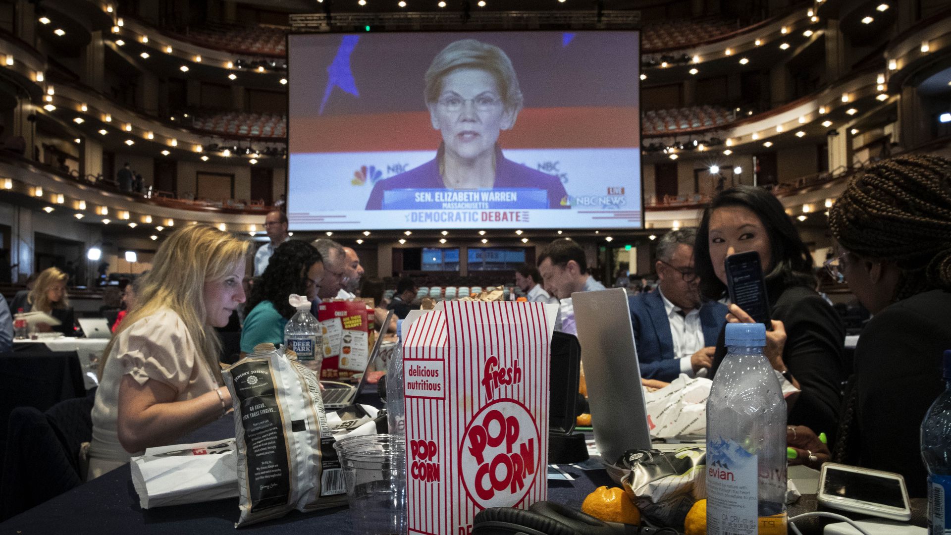 Reporters eat popcorn while watching Democratic debate