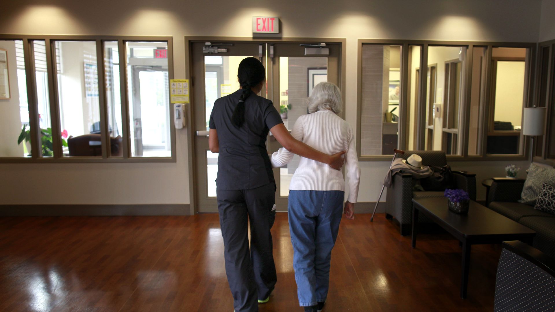 Photo of nurse walking an Alzheimer's patient down the hall, with her arm around her back