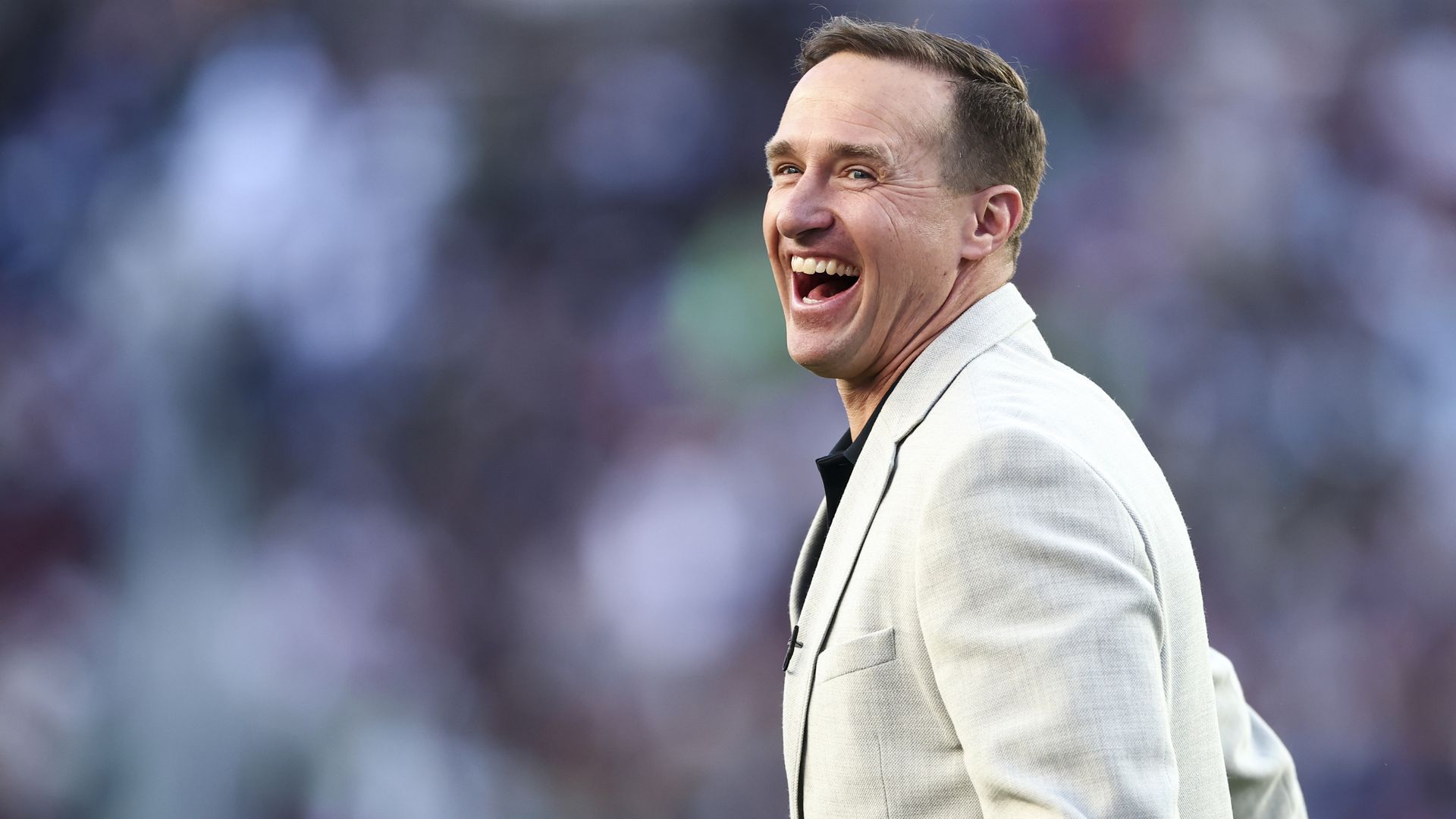 Drew Brees looks over his shoulder with a giant smile.