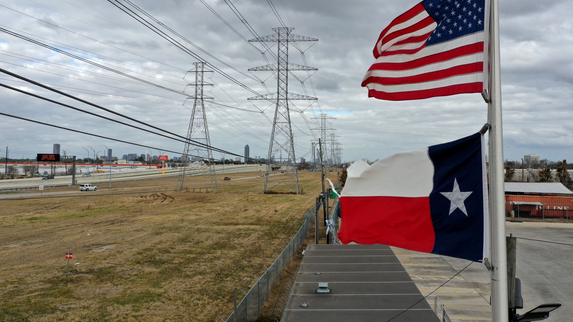 The U.S. and Texas flags fly in front of high voltage transmission towers on February 21, 2021 in Houston, Texas.