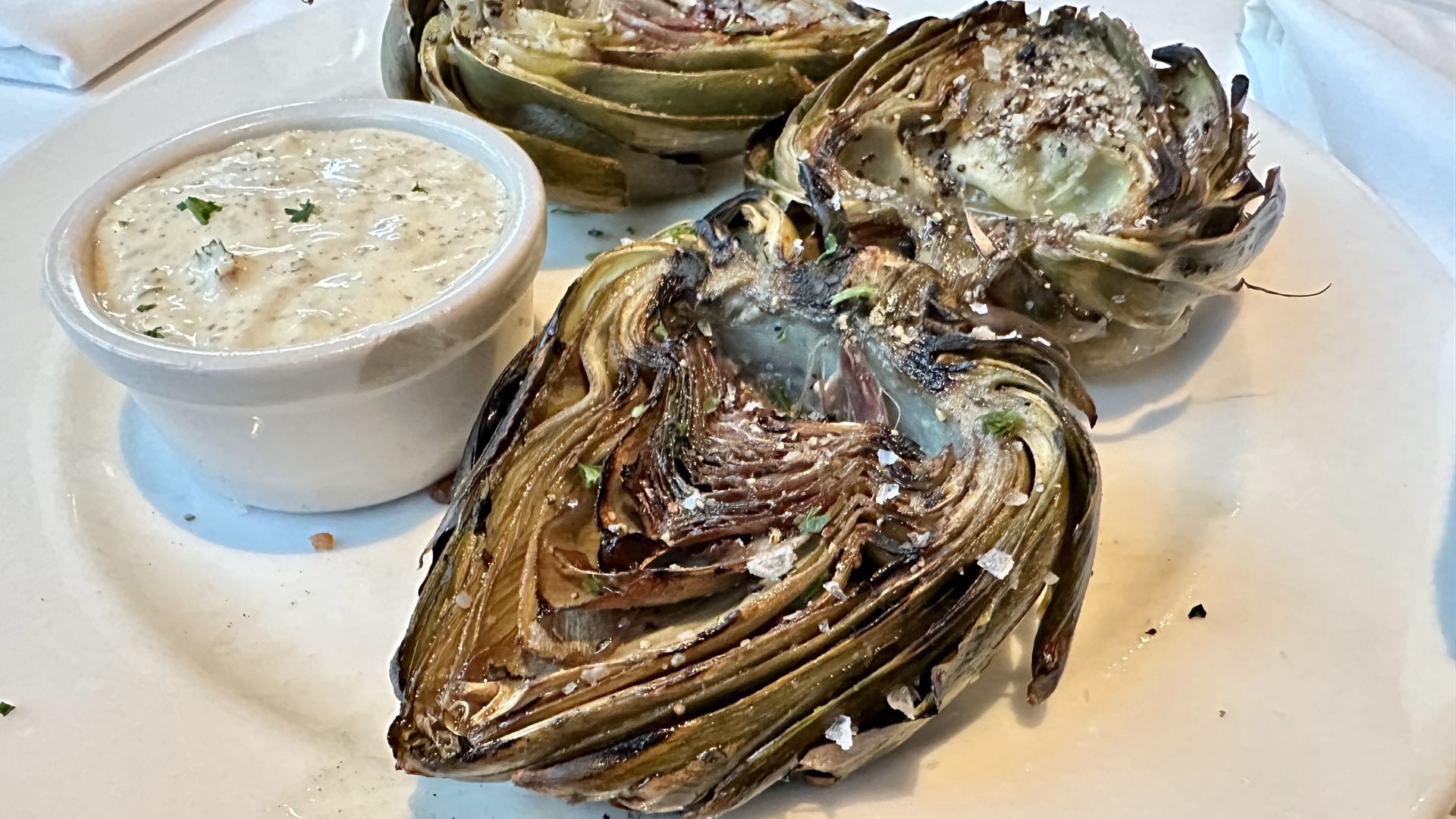 Photo shows three artichoke halves with a ramekin of spicy remoulade sauce