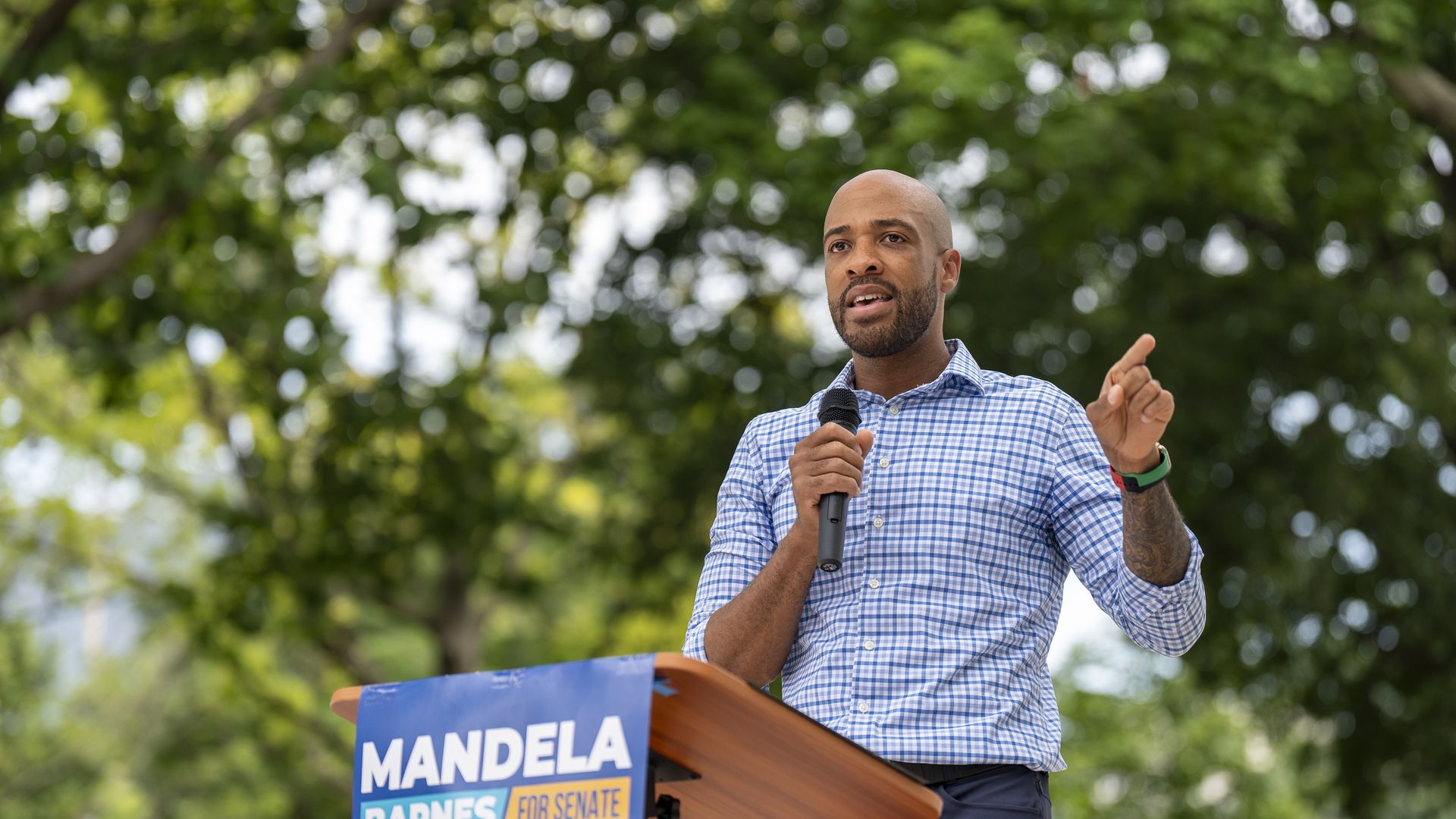 Wisconsin's former Lt. Gov. Mandela Barnes speaking to supporters outside holding a microphone in his right hand.