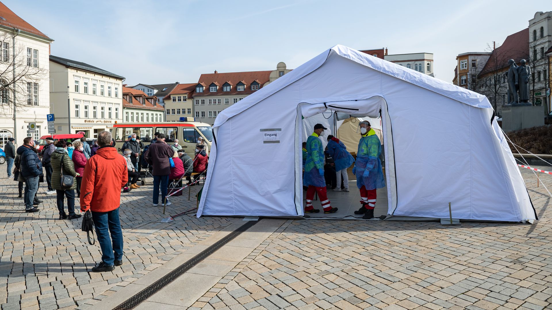 Photo of a tent set up for COVID testing and people standing outside socially distanced