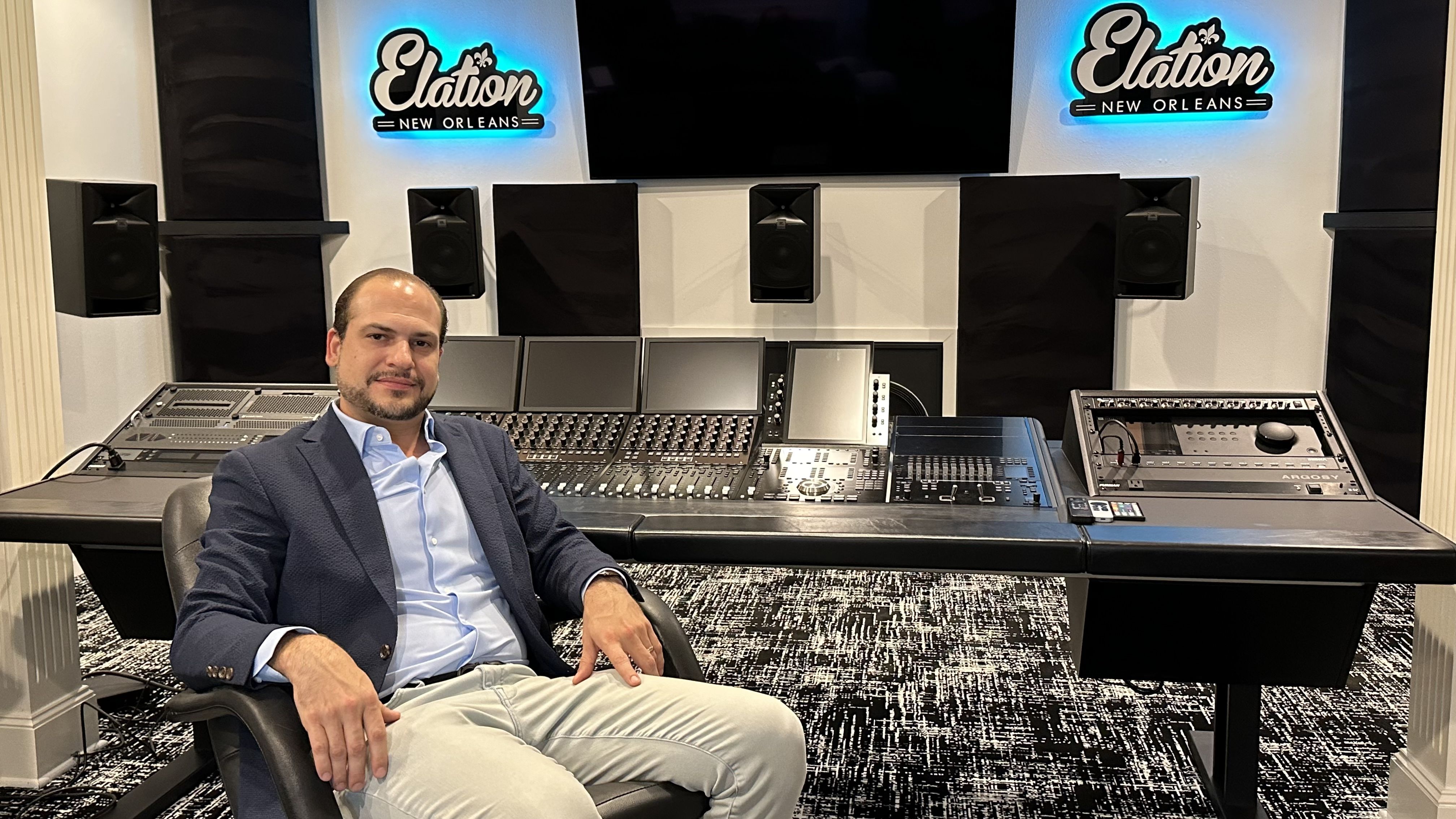 Photo shows David Adams sitting at a desk with mixing boards in Metairie.