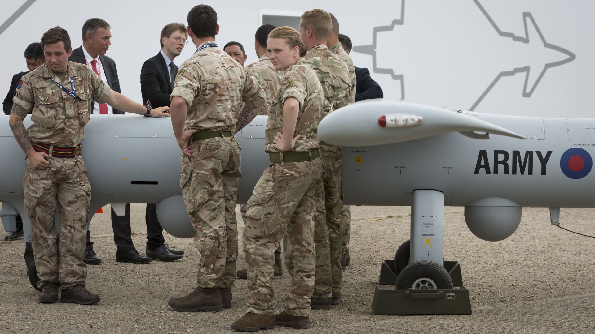 British soldiers, including one woman, in uniform stand near plane.