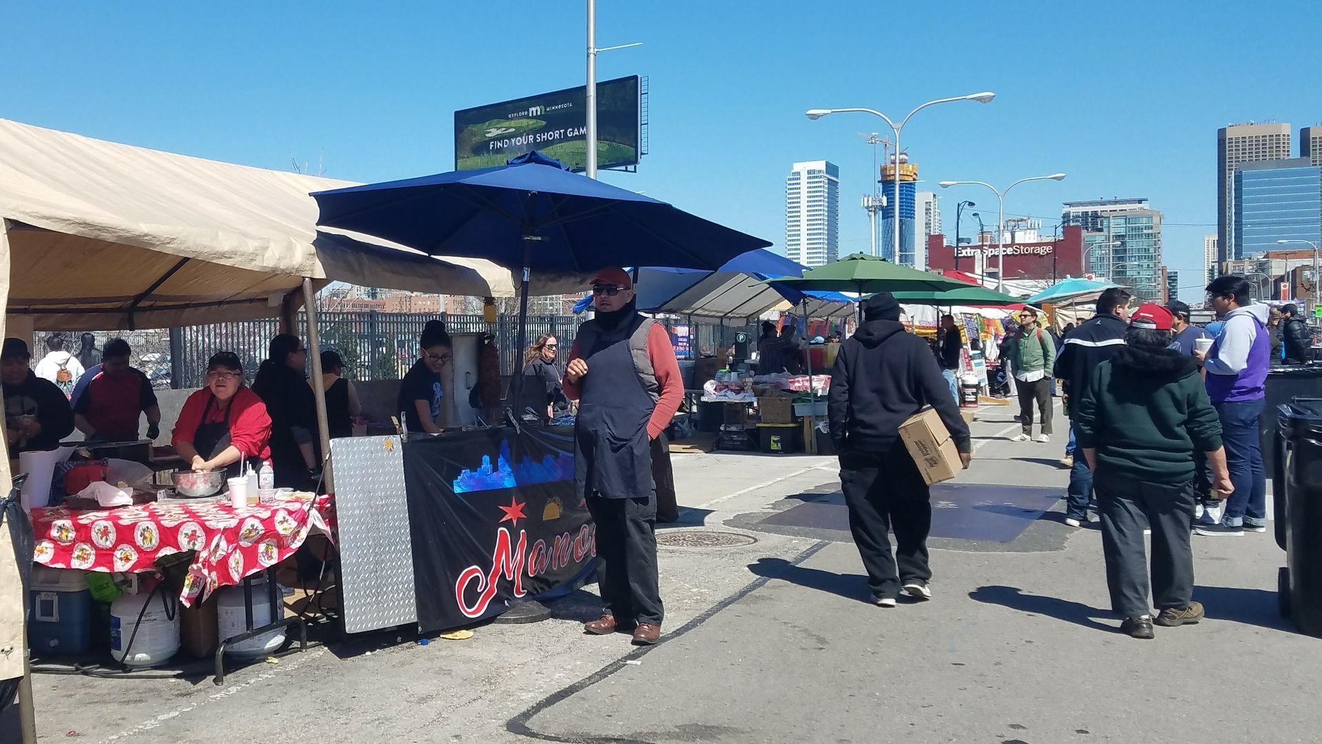 Photo of people strolling on street looking at tents of food and merchandise