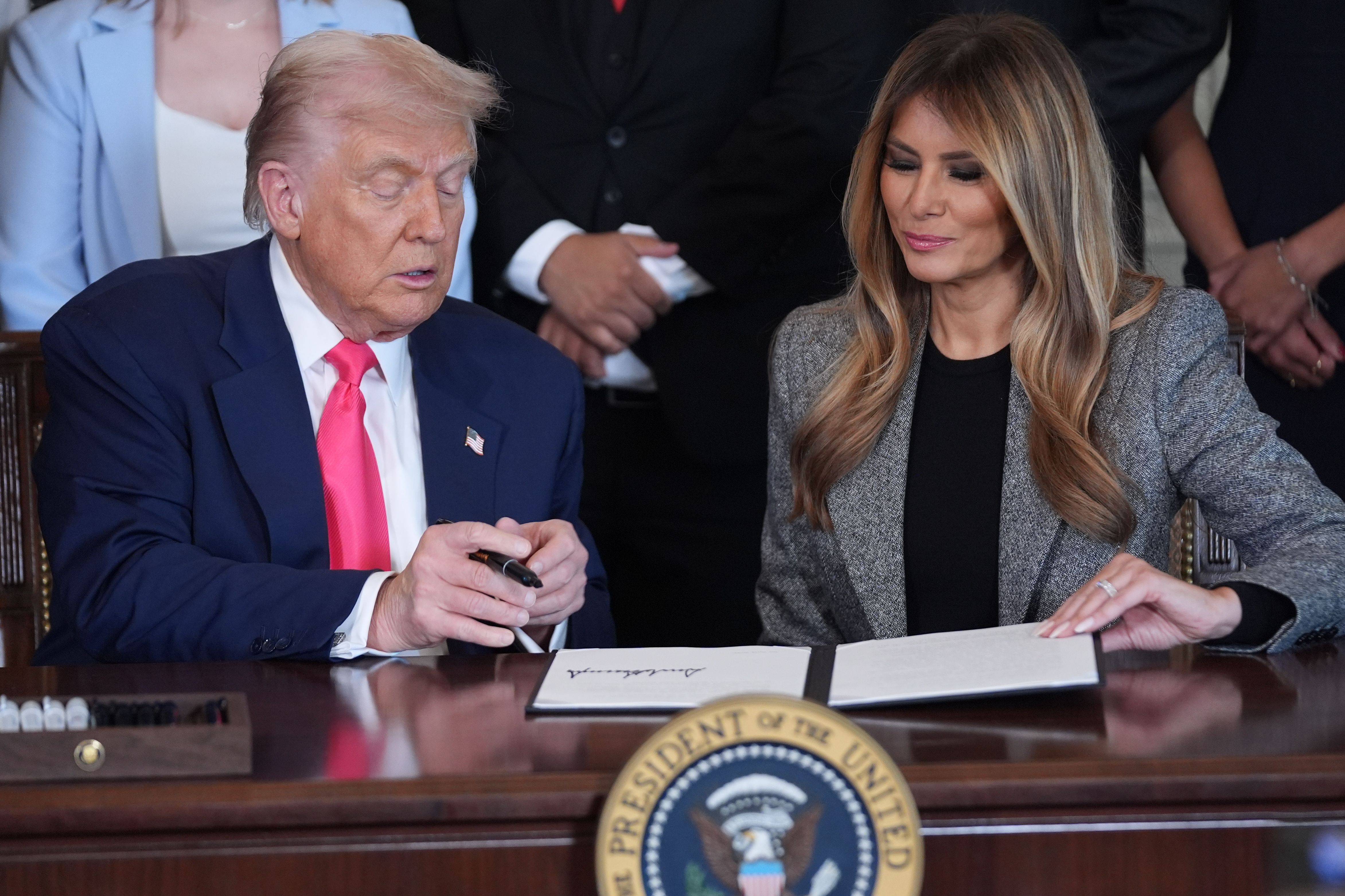 President Donald Trump signs an executive order as first lady Melania Trump watches during an event on foster care in the East Room of the at the White House, Thursday, Nov. 13, 2025, in Washington. (AP Photo/Evan Vucci)