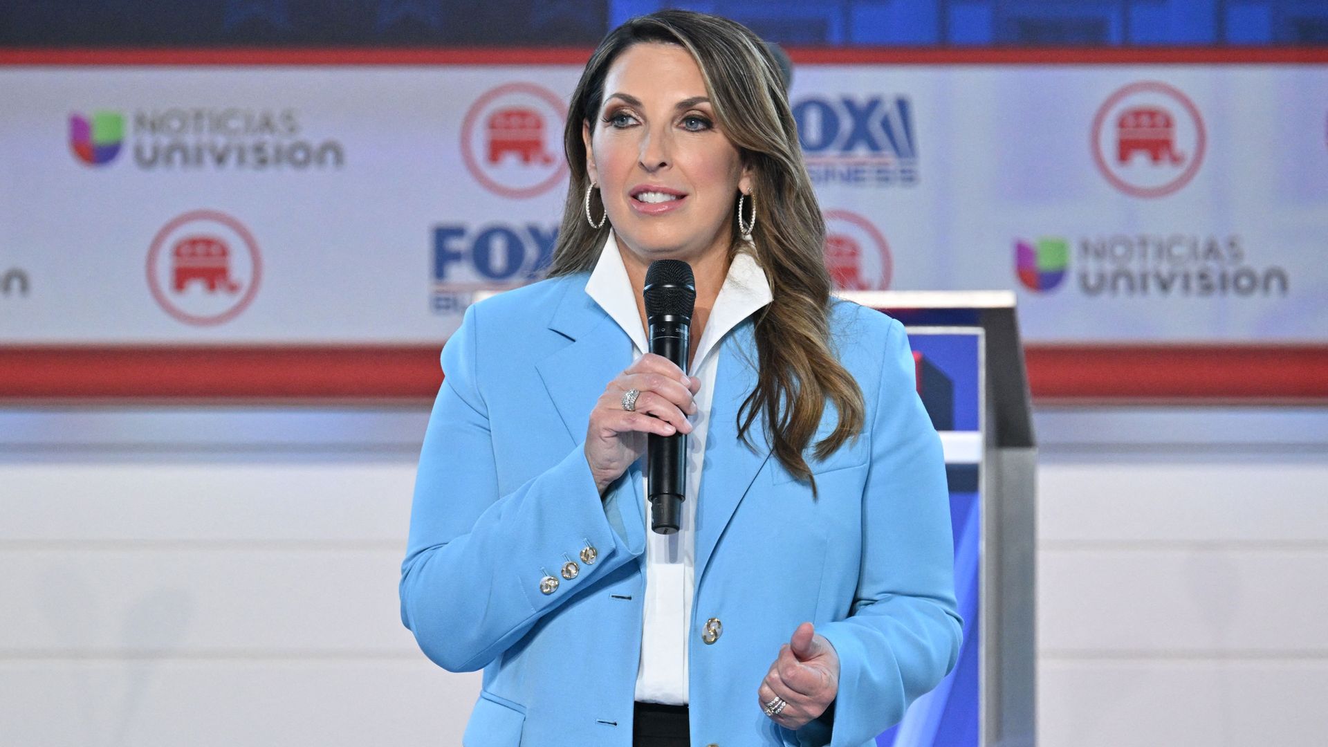 RNC chair Ronna McDaniel, in a light blue jacket and holding a microphone