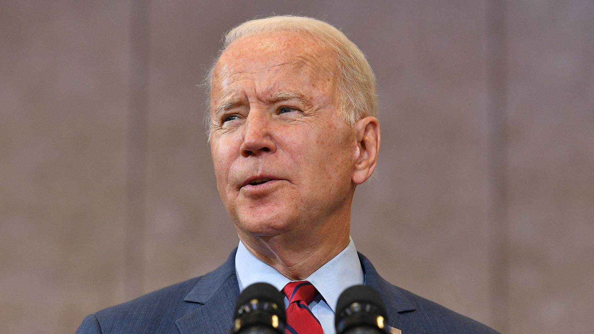 Photo of Joe Biden from the shoulders up speaking into microphones