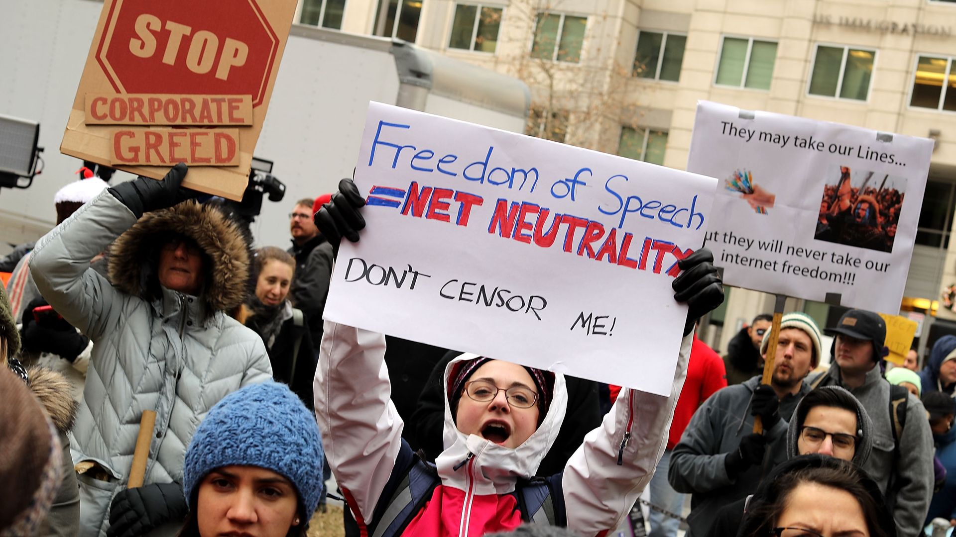 Protestors hold signs demonstrating against the end of net neutrality rules