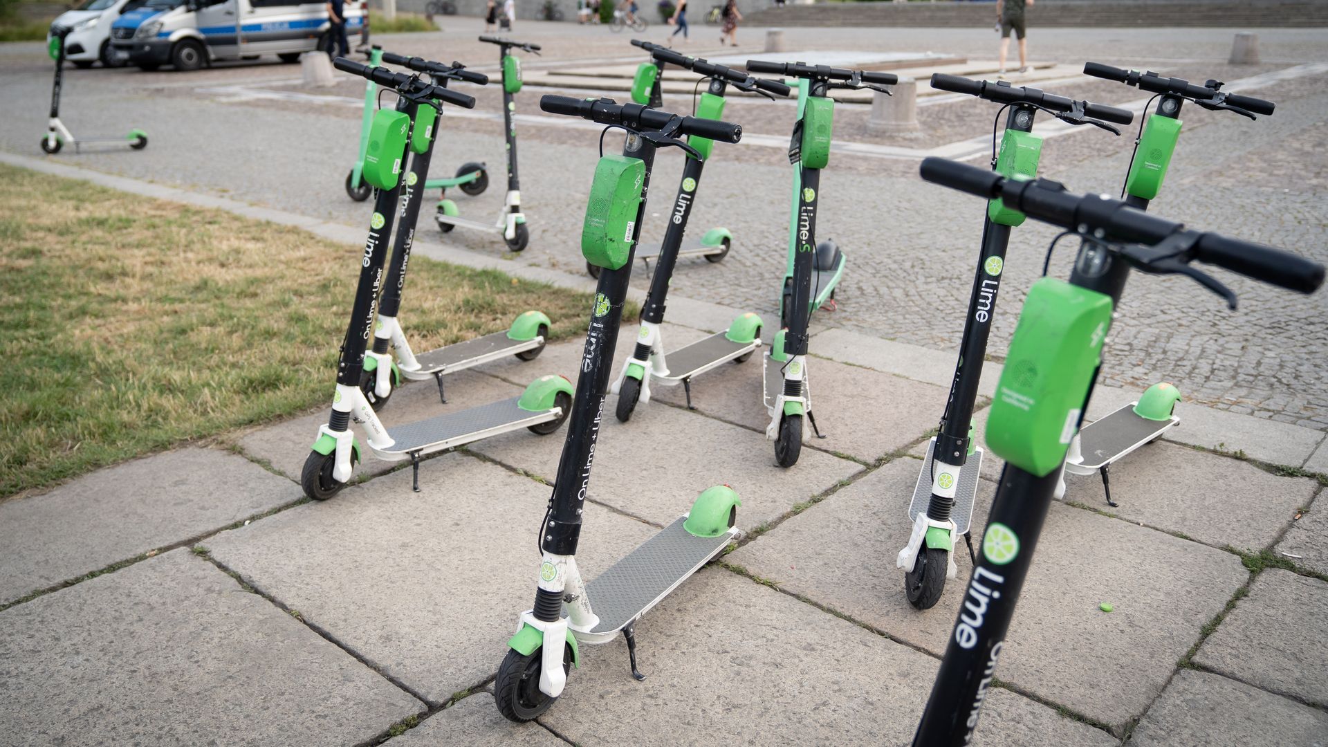 Several lime electric scooters on a sidewalk.