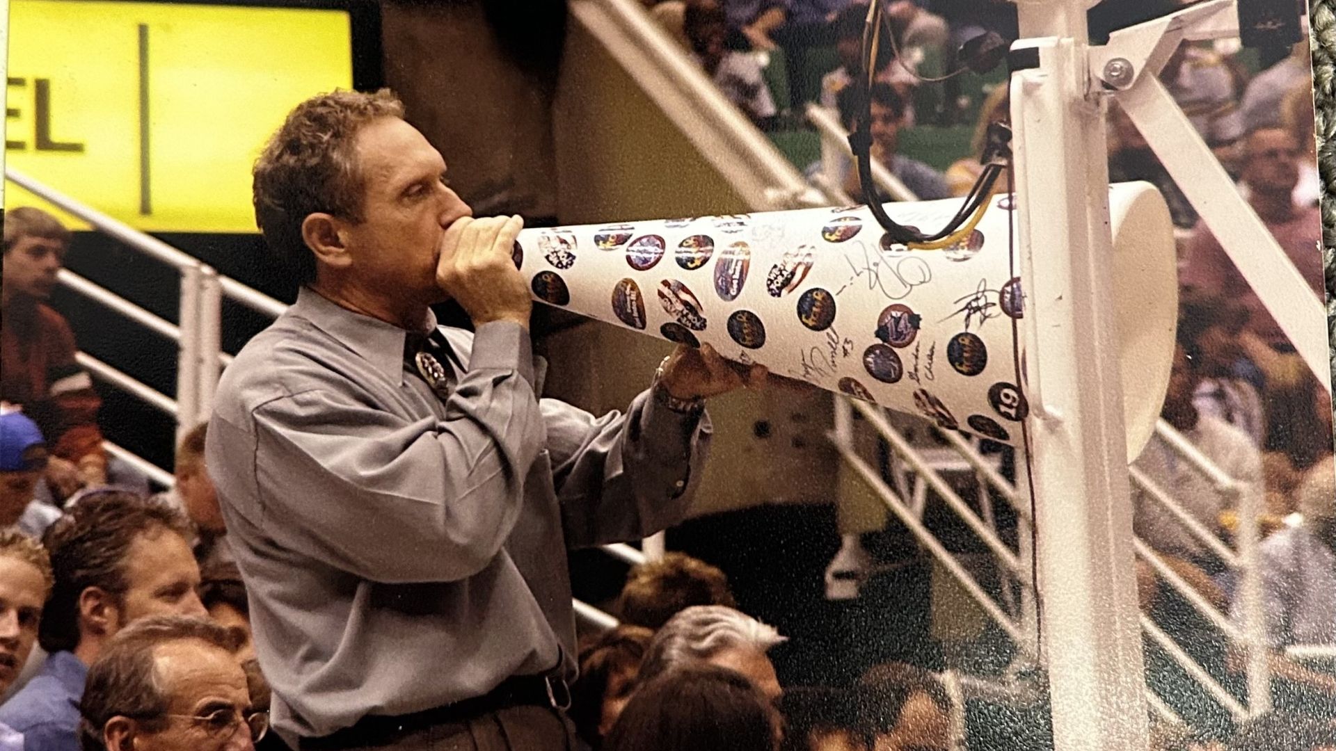 A man speaks into a bullhorn at a basketball game.