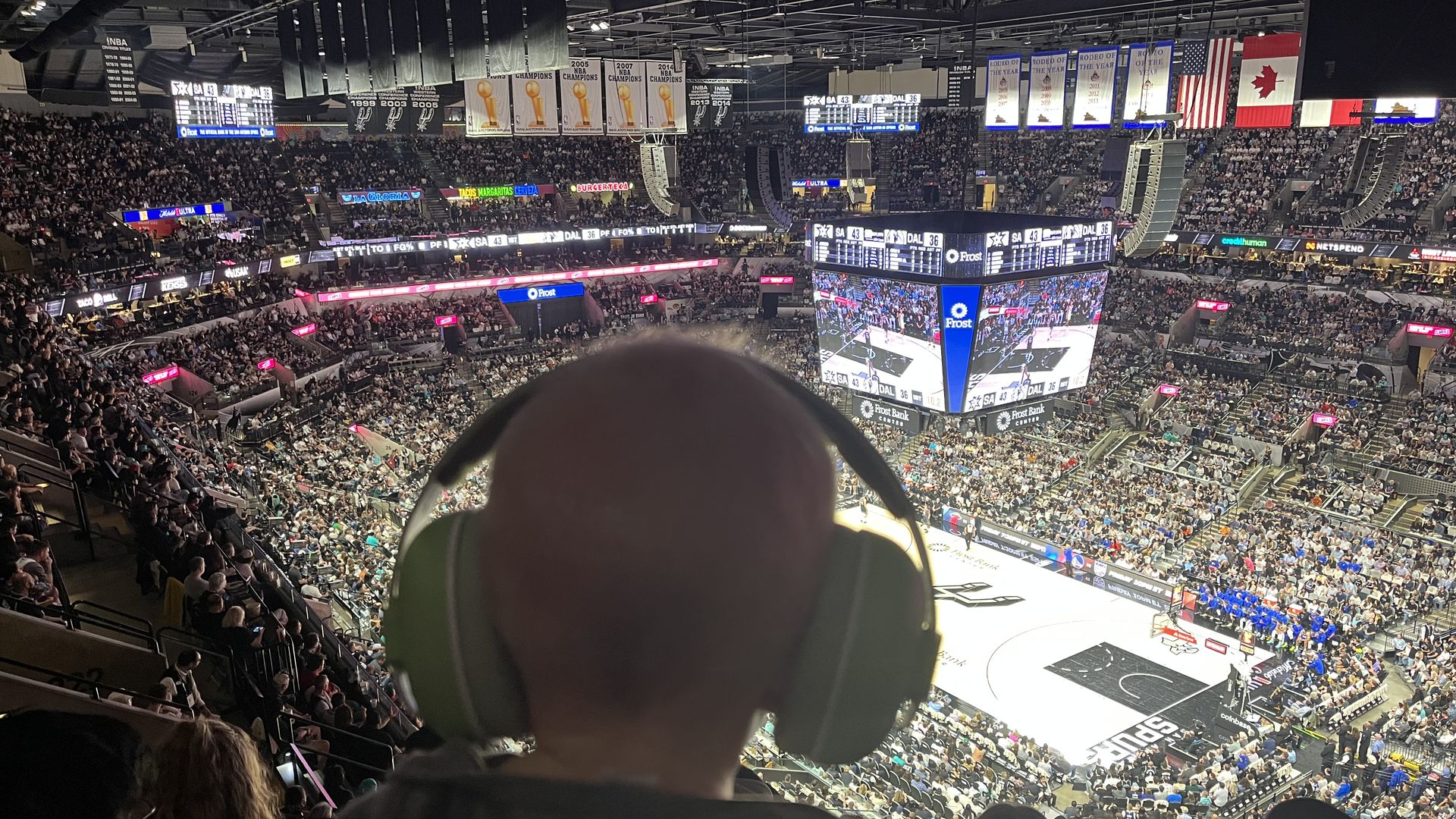 A child with noise-canceling headphones watches a basketball game.