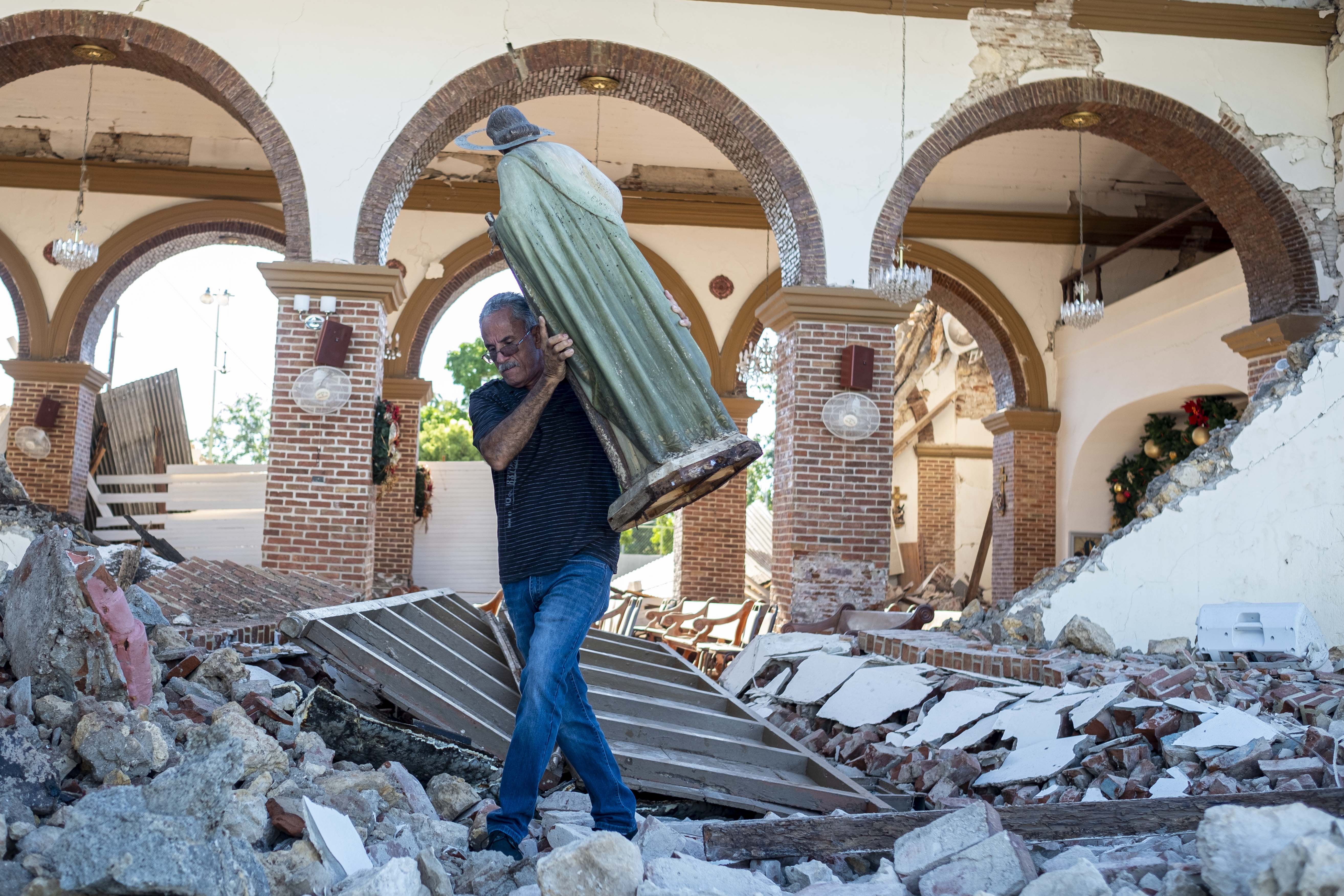 A man carries a St. Jude statue from the Inmaculada Concepcion church ruins that was built in 1841 and collapsed after an earthquake hit the island in Guayanilla