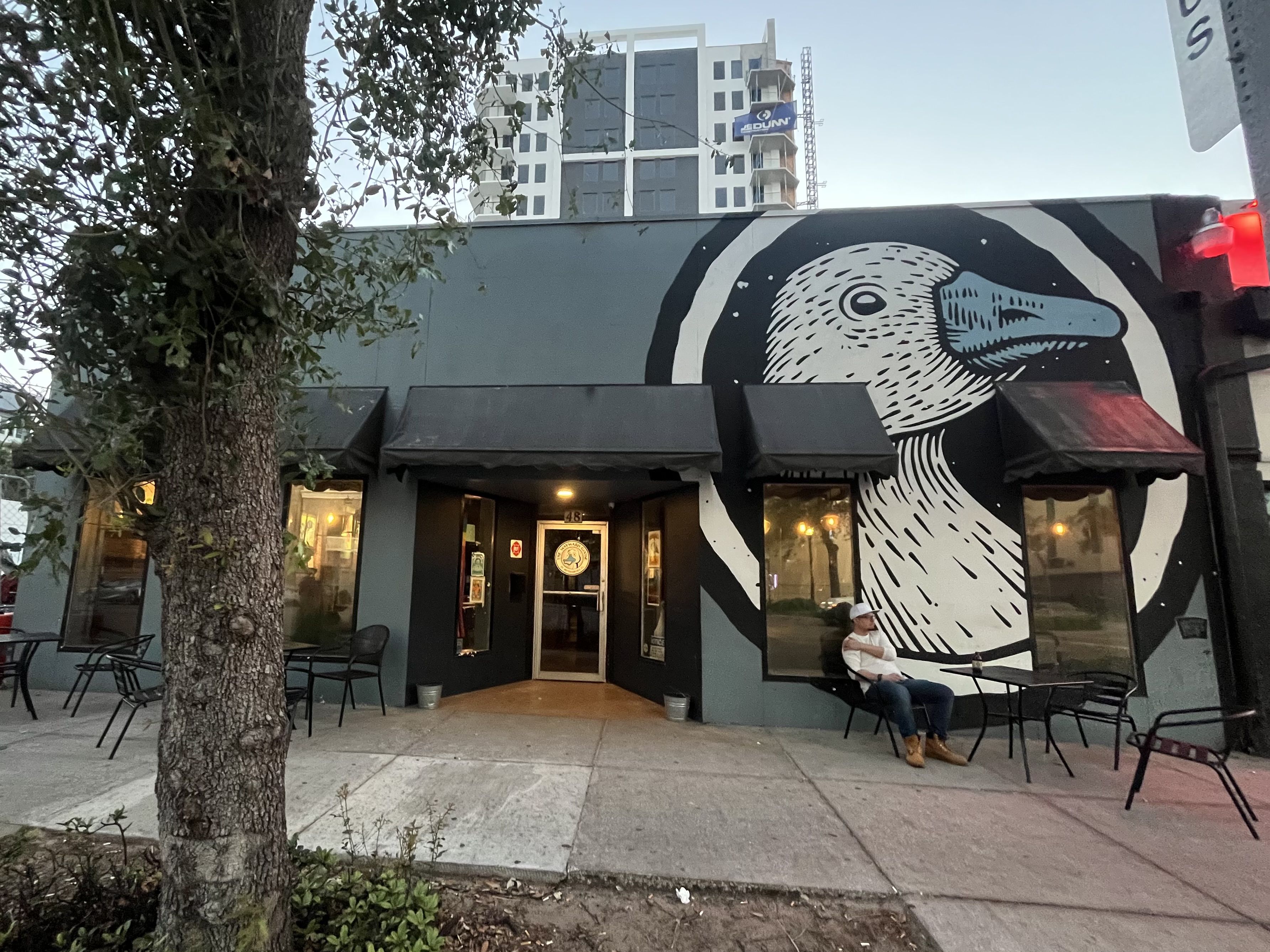 The front entrance of a bar with a mural of a goose with a blue beak painted on the outside.