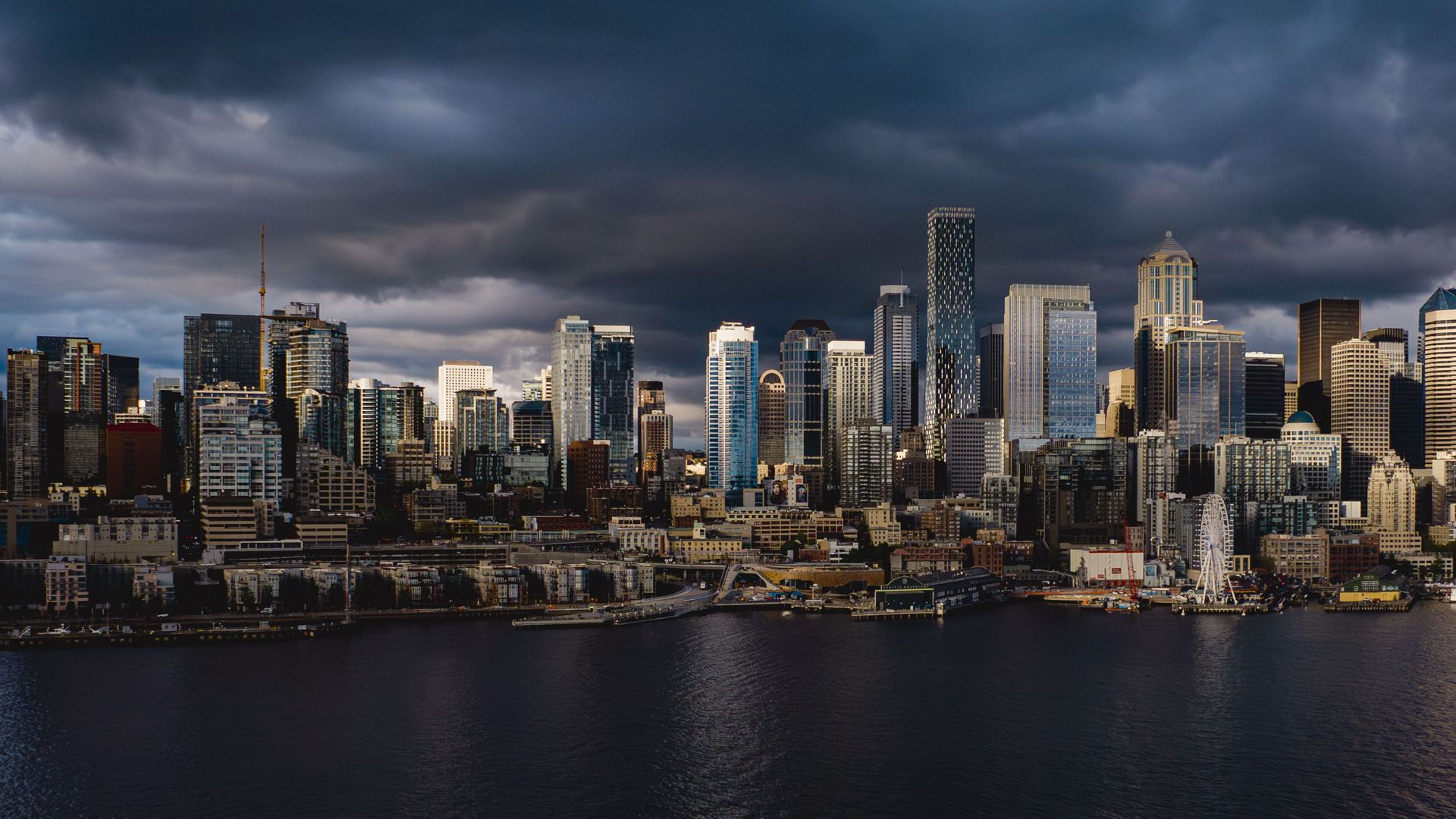 Dark storm clouds loom over downtown Seattle  as the sun sets. 