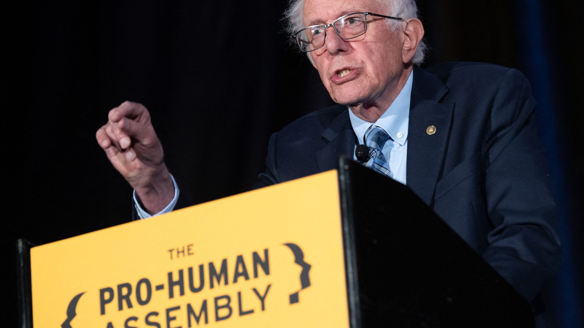 A person in a suit and tie speaks at a podium